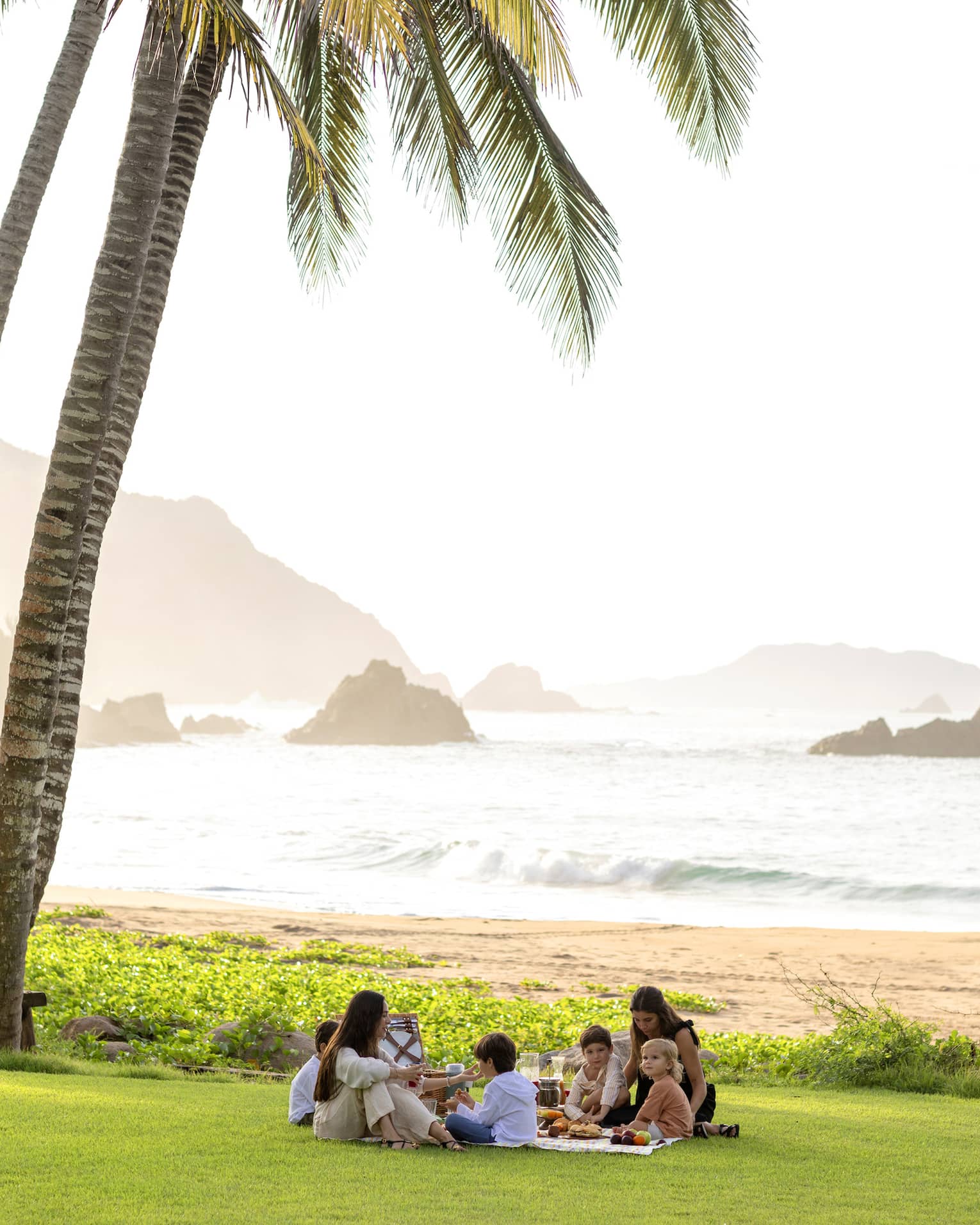 Many guests having a picnic surrounded by palm trees.