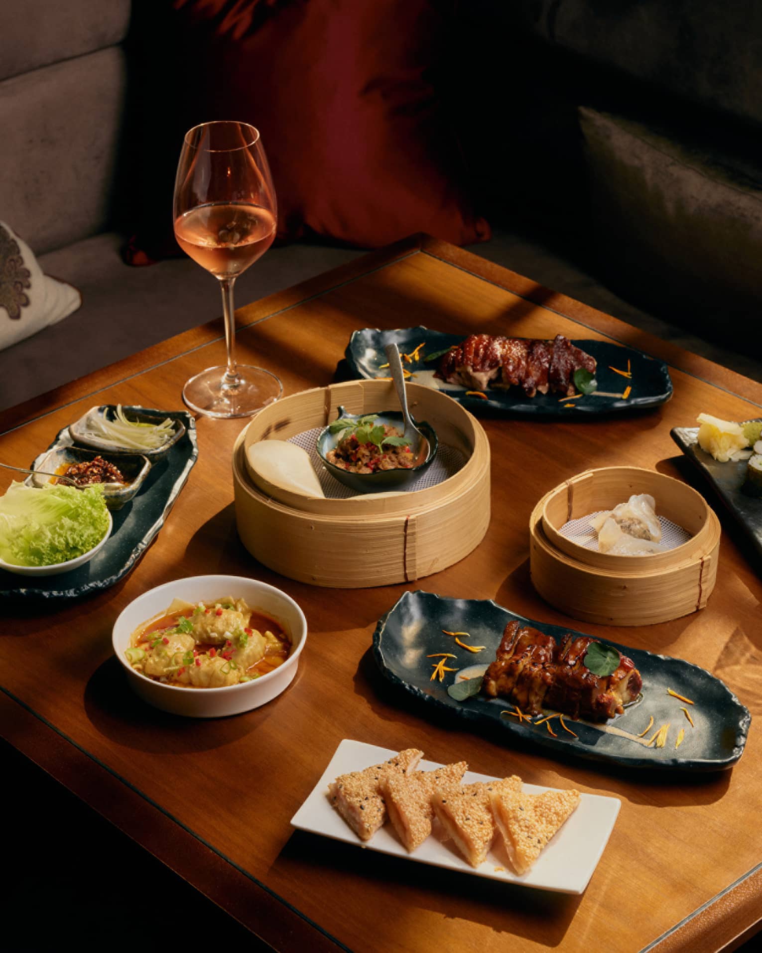 Assorted dim sum and glasses of wine on square wooden table