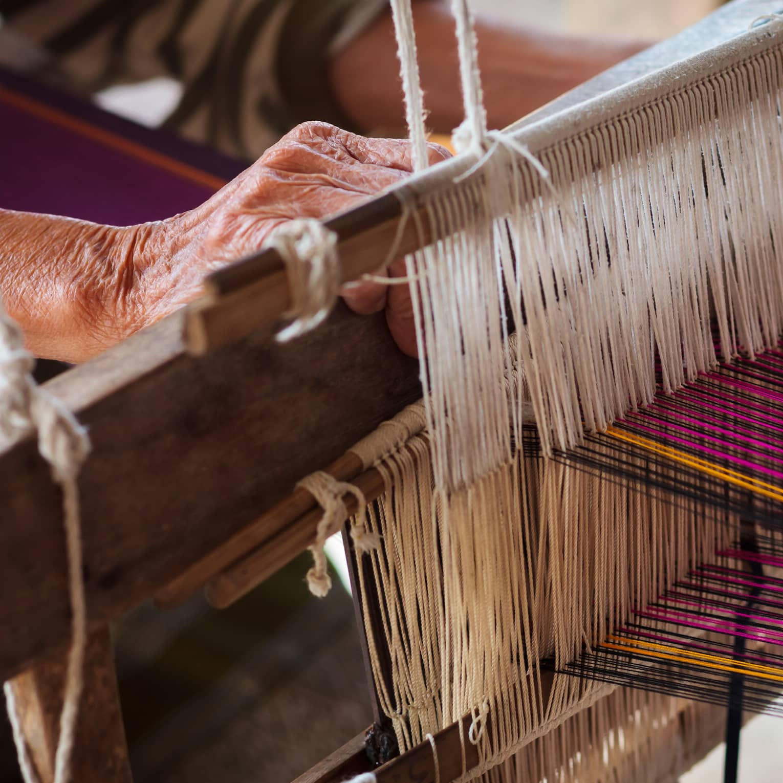 Person using a loom with multi-coloured thread