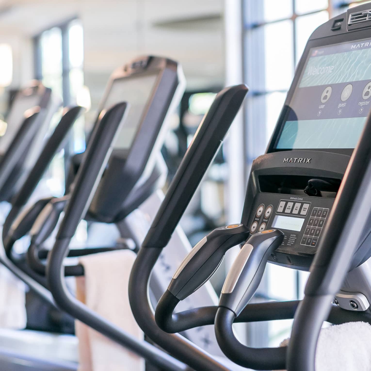 Close-up of cardio elliptical machines in a row in fitness facility