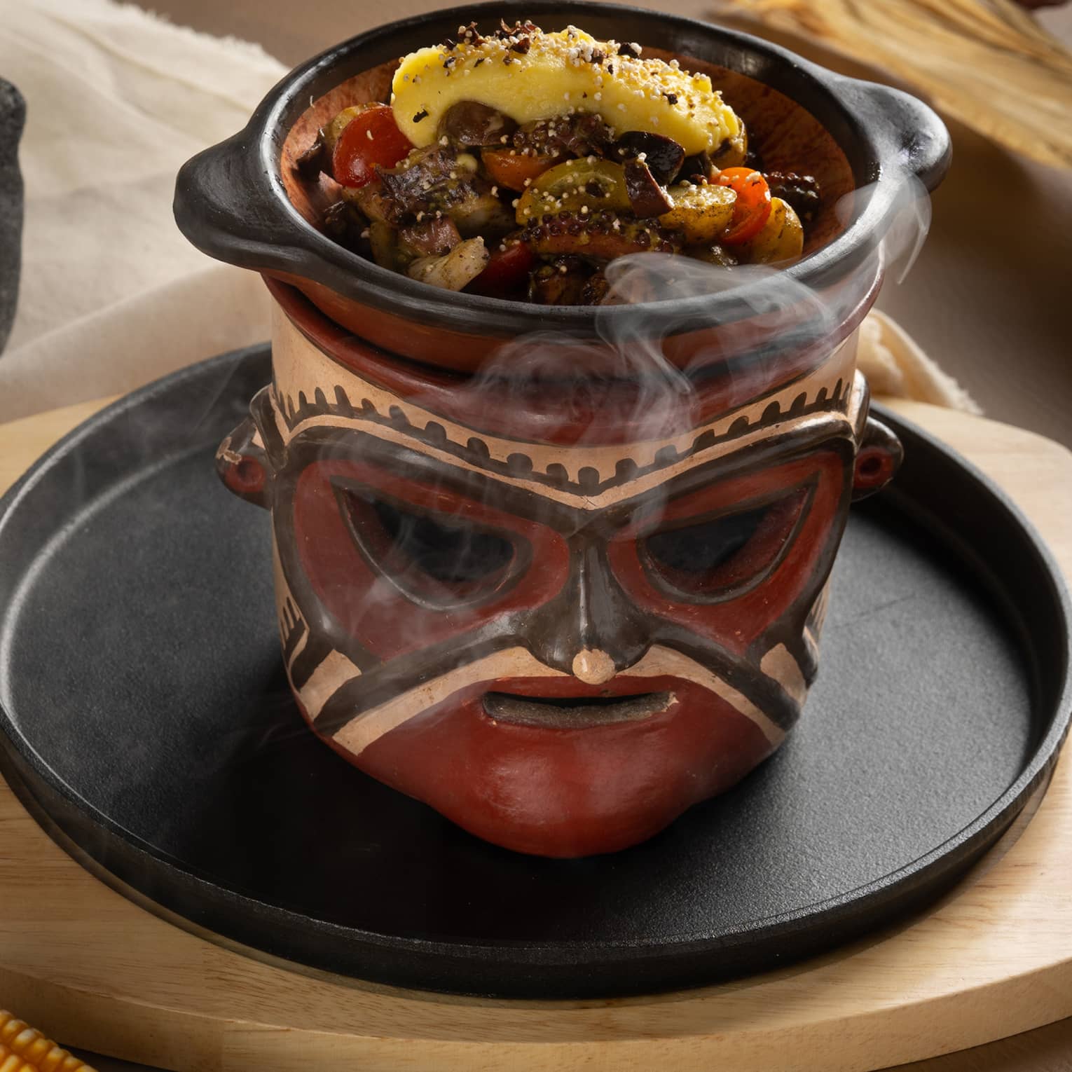 Octopus Causa ?Chorotega Style? served on a black plate in a steamer shaped like a decorative face