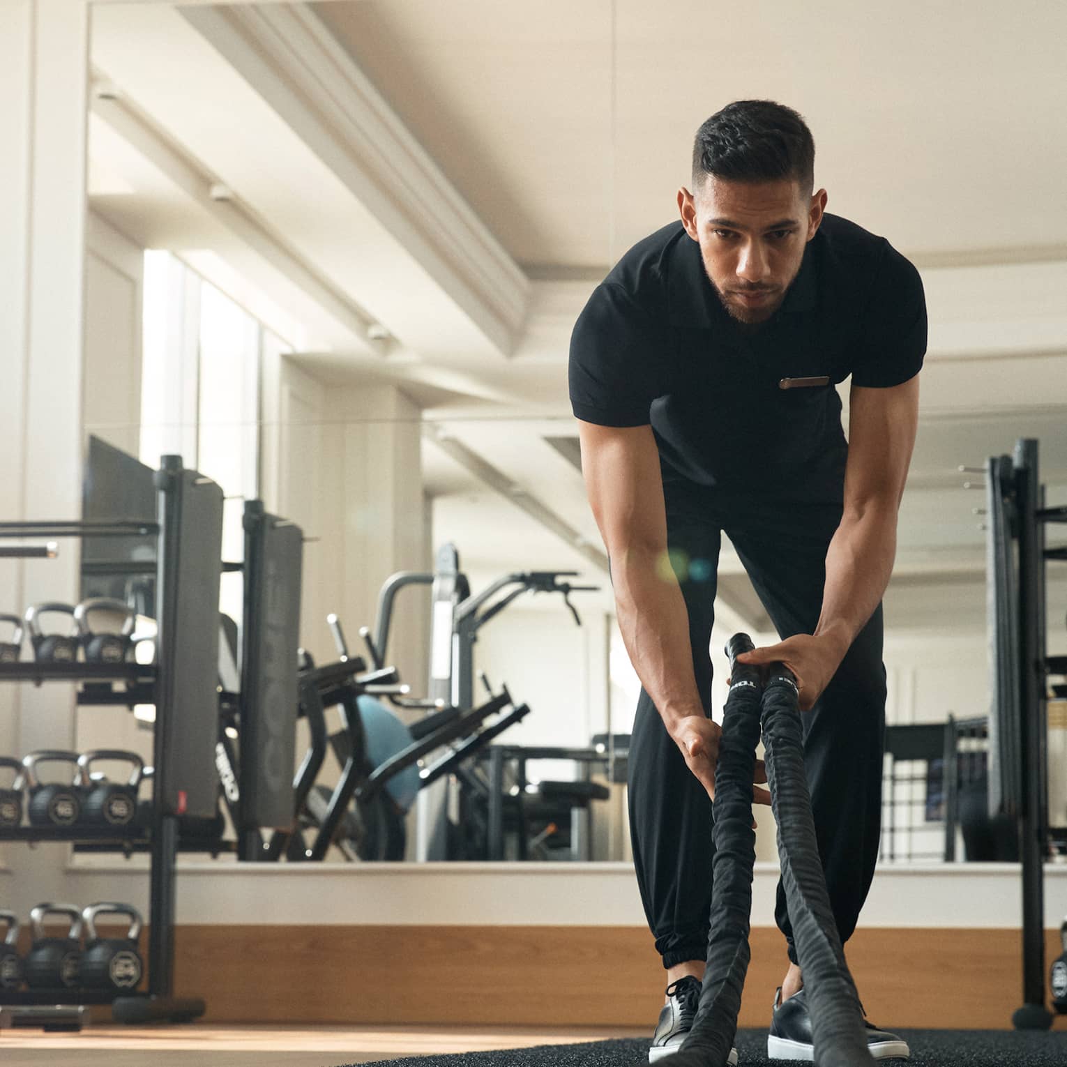 Man works out in fitness room using a heavy rope