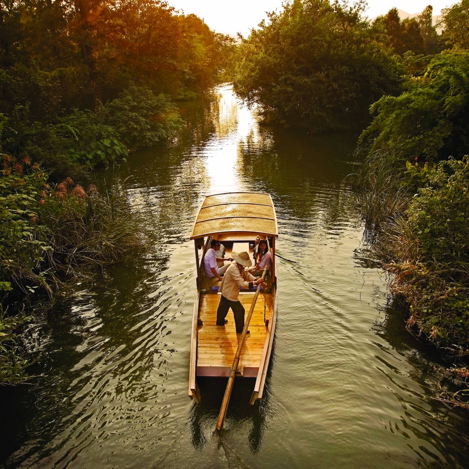 Traditional Chinese wooden boat sails down river in Xixi Wetland National Park
