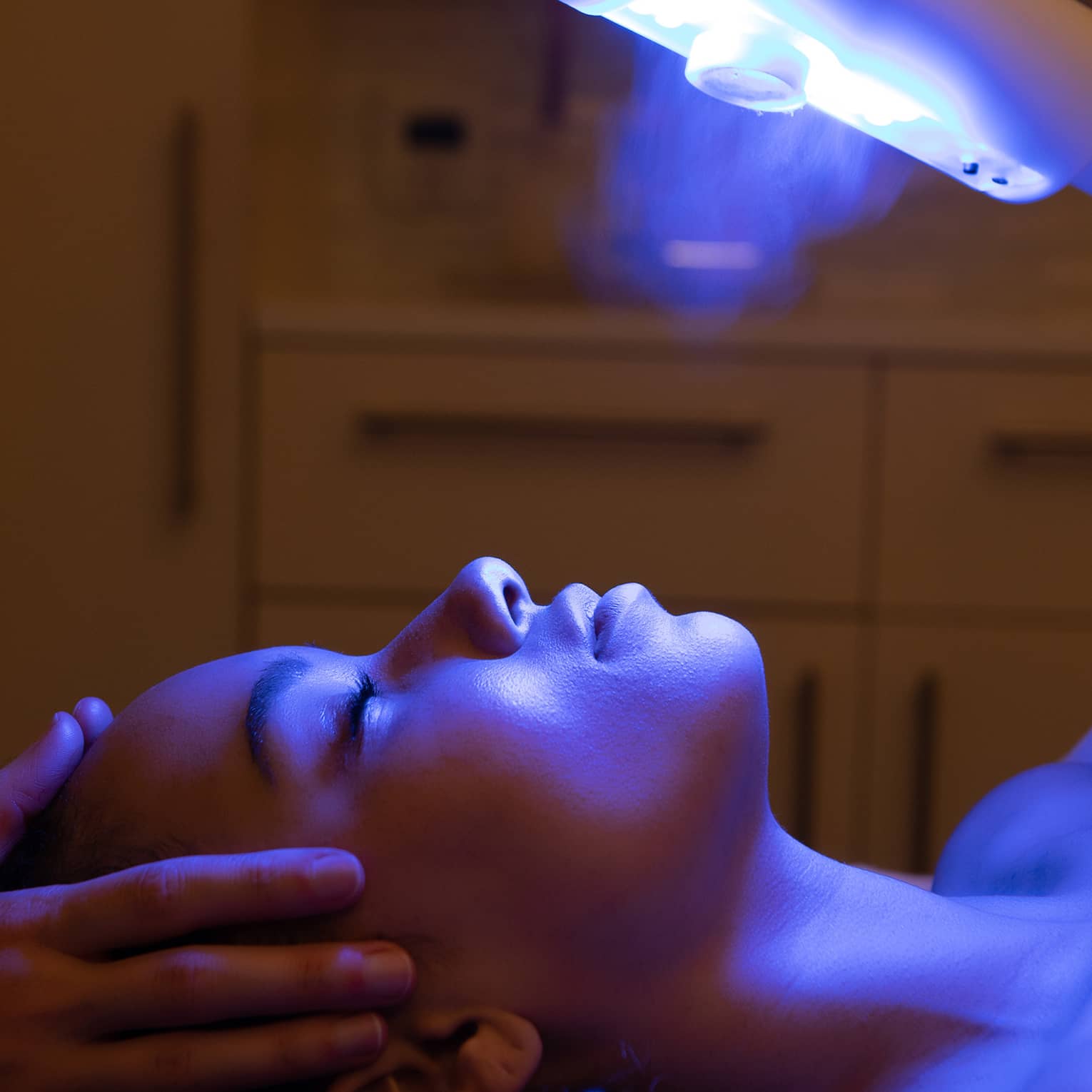 A guest laying on a spa table and receiving a light therapy treatment 
