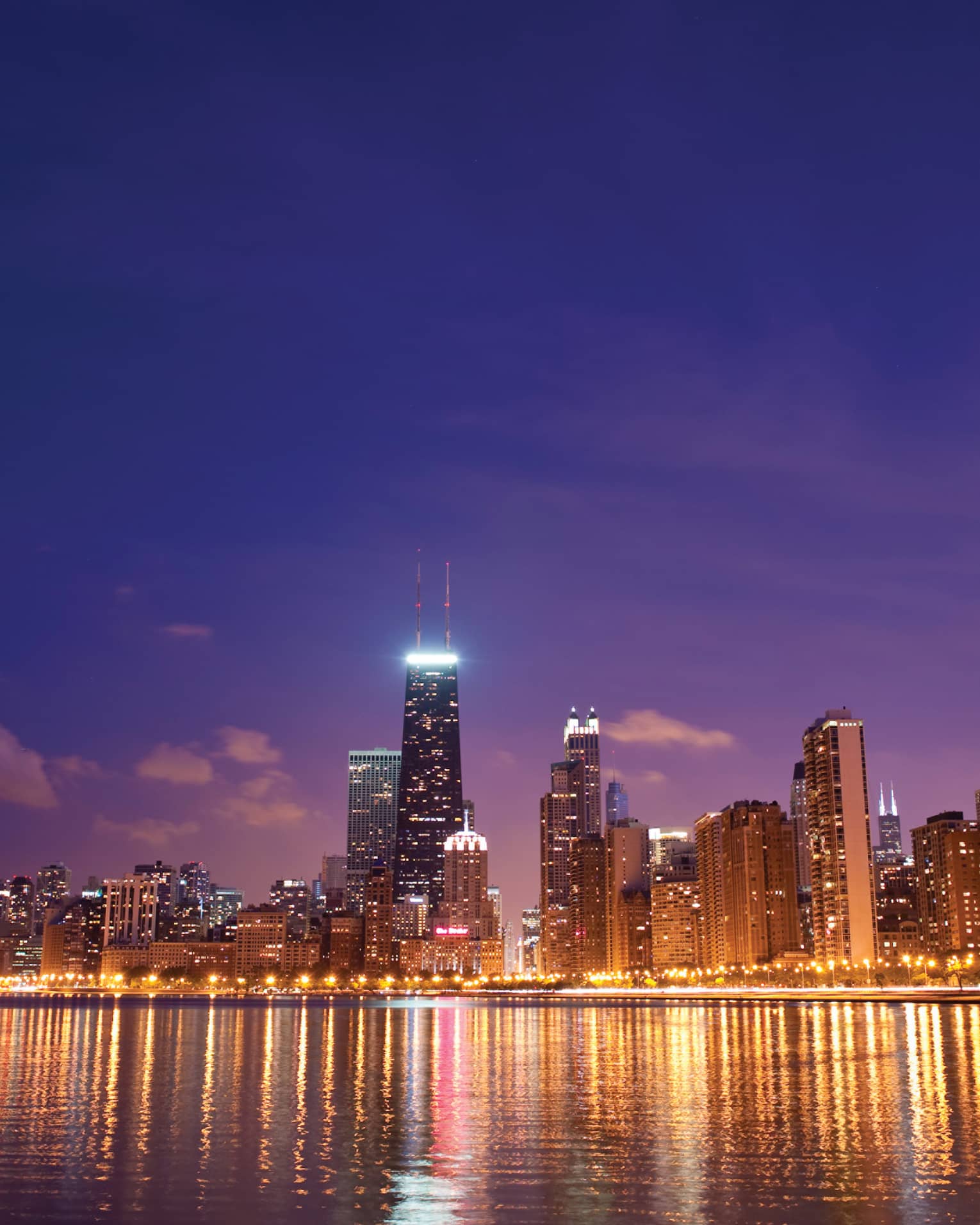 Chicago skyline at night on water with skyscrapers light up with lights