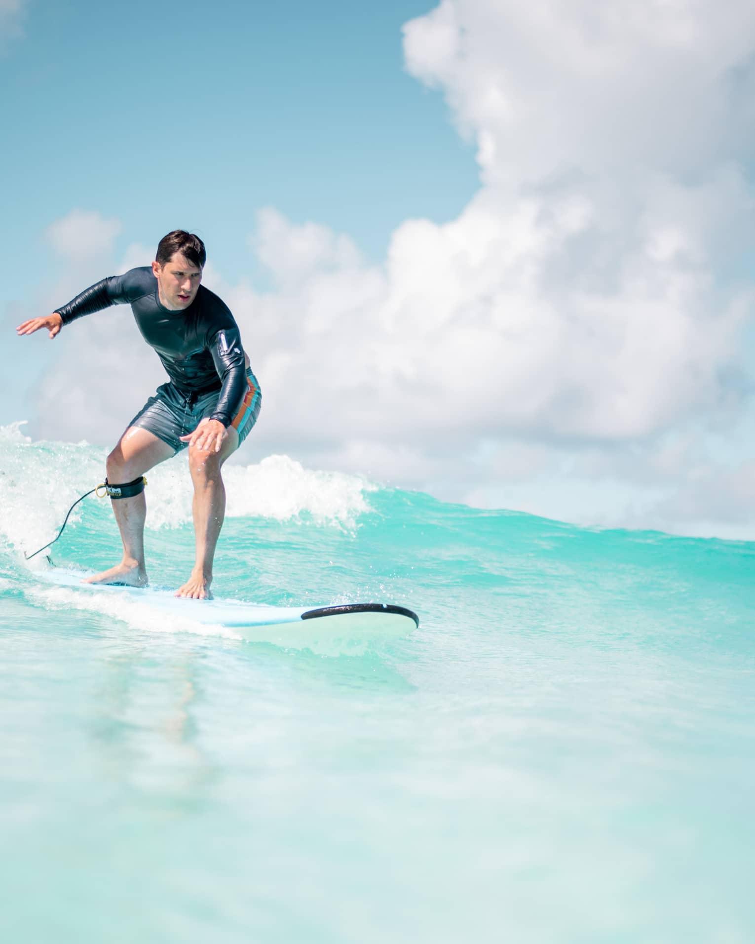 Man balances on surf board over wave