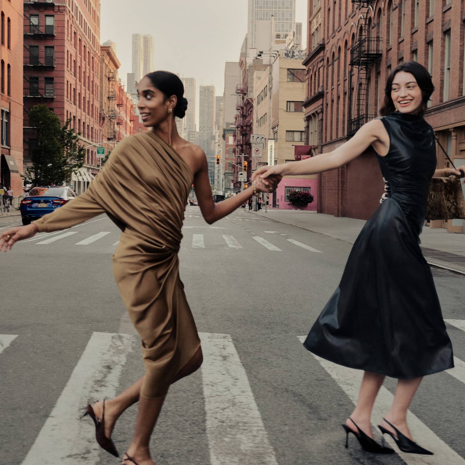 Two women holding hands cross a street in New York City.