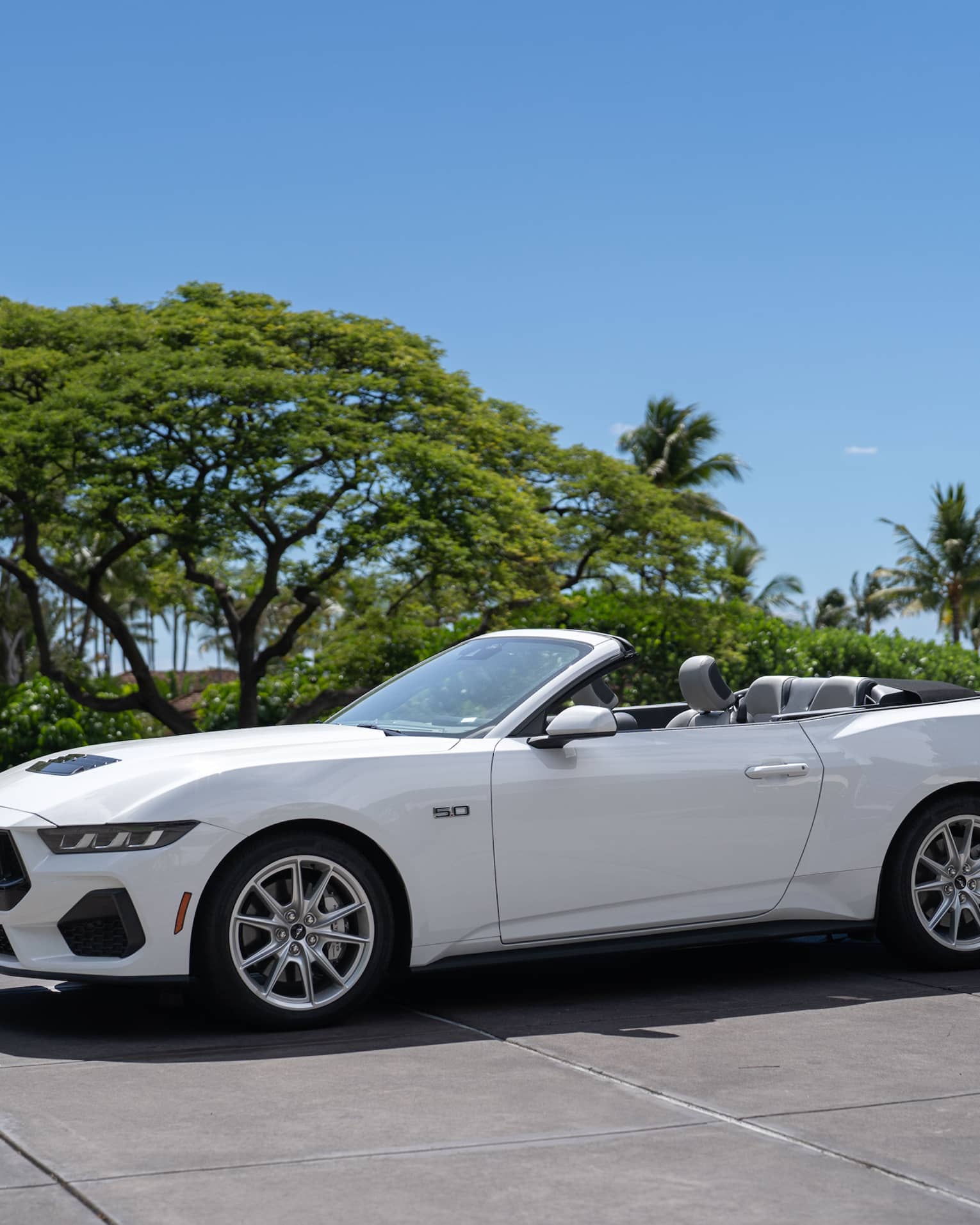White convertible car parked in front of tropical beach setting