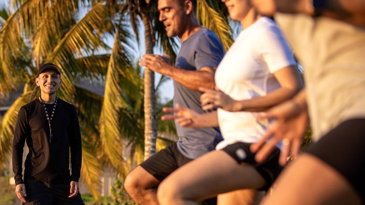 Fitness instructor leading an outdoor workout class with three guests.