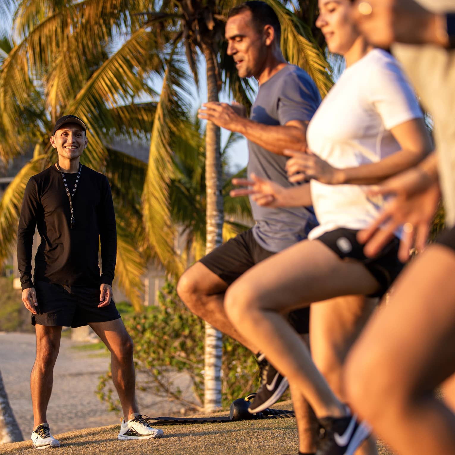 Fitness instructor leading an outdoor workout class with three guests.