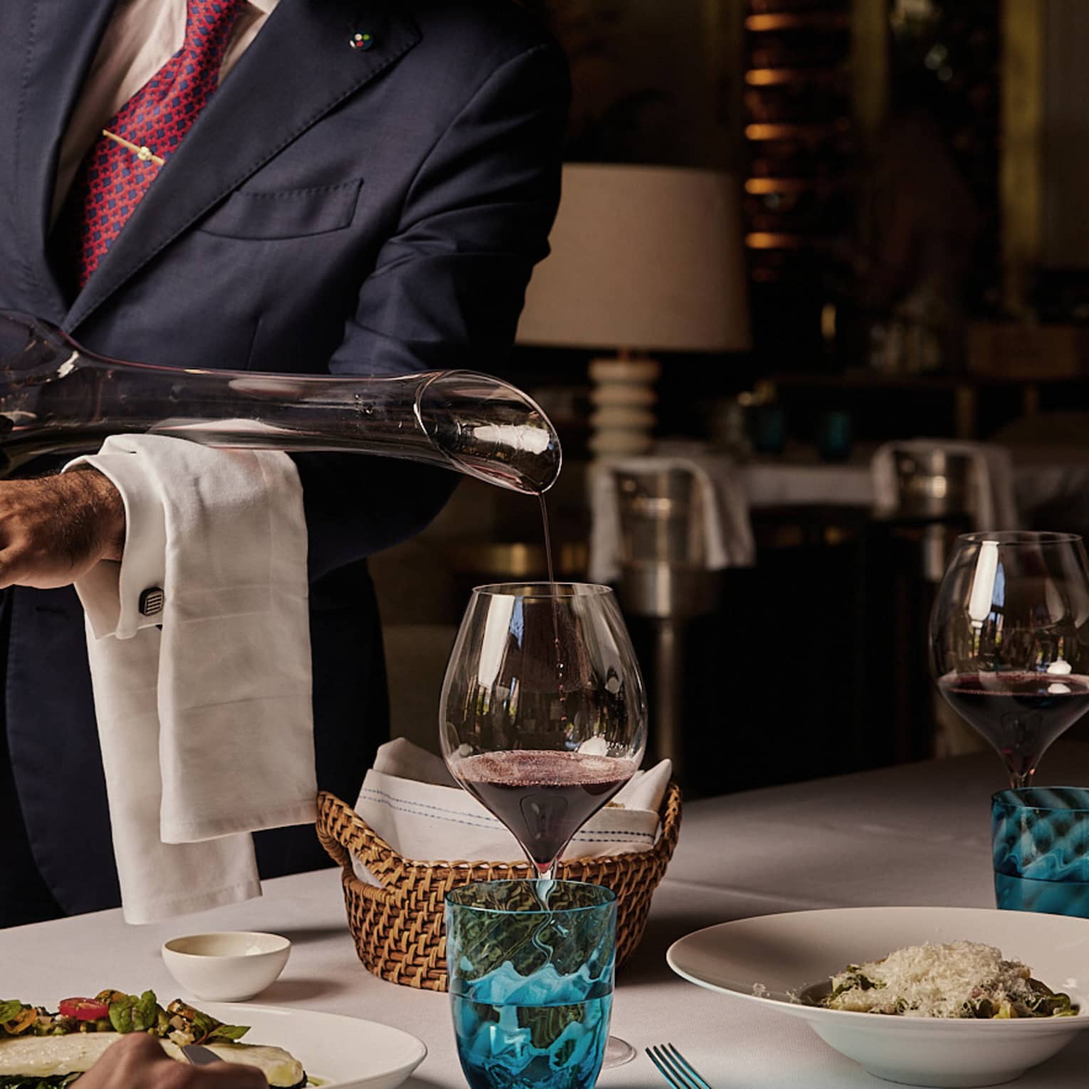 Red wine being poured into a glass from a long-necked decanter