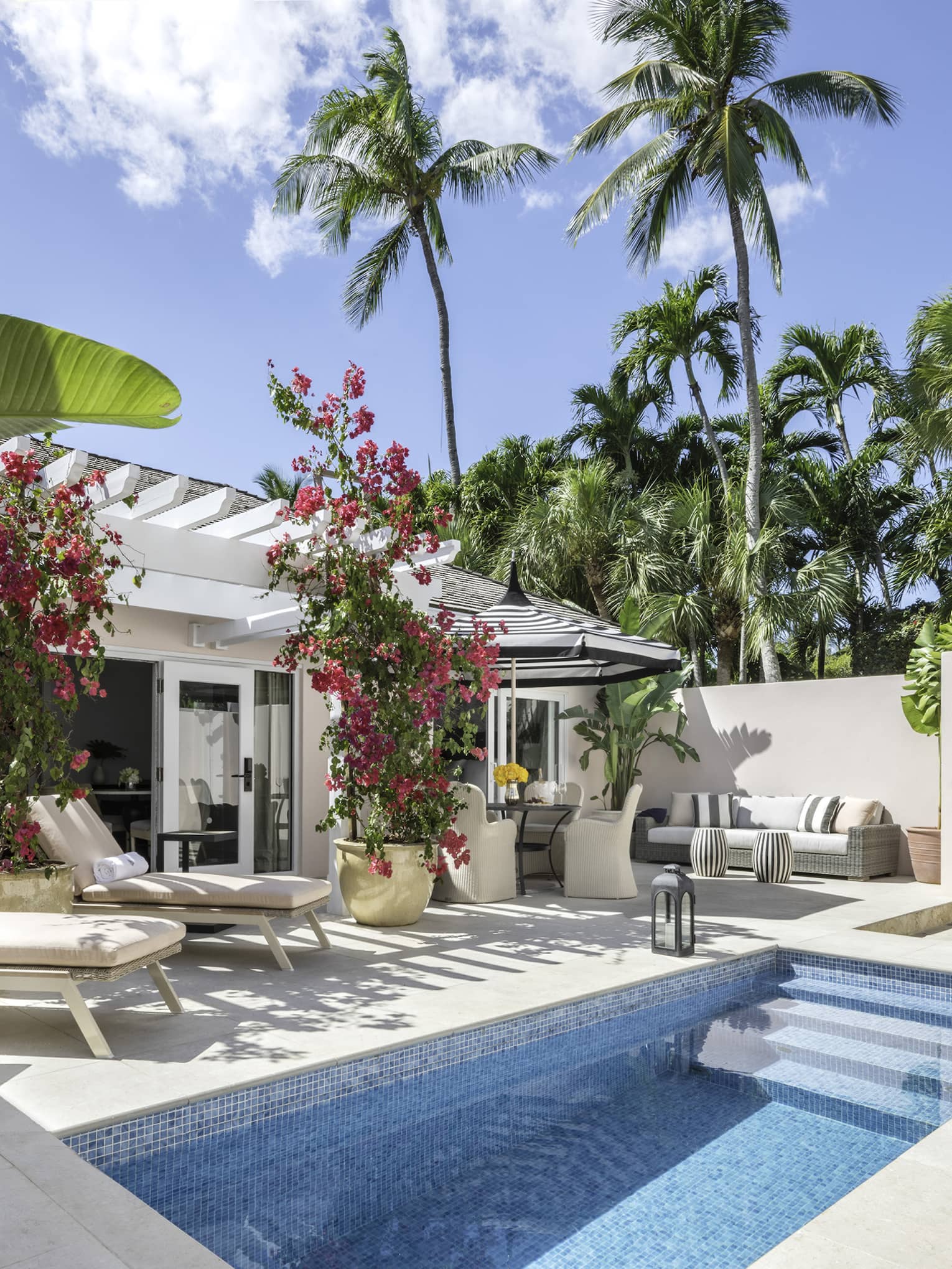 Resort bungalow with a private plunge pool, lounge chairs and lush tropical plants