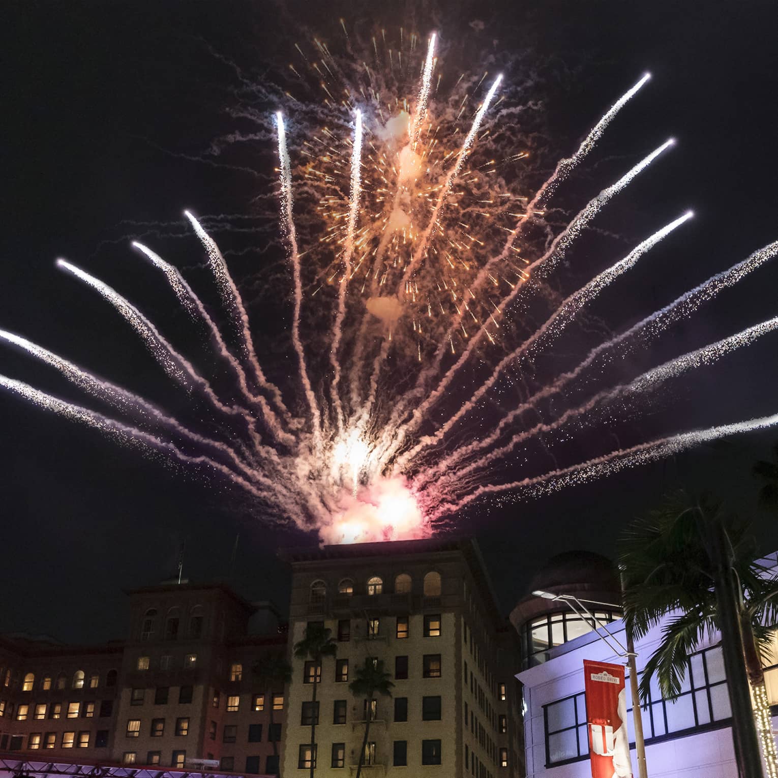 Fireworks exploding over buildings and large crowd during the holiday season.