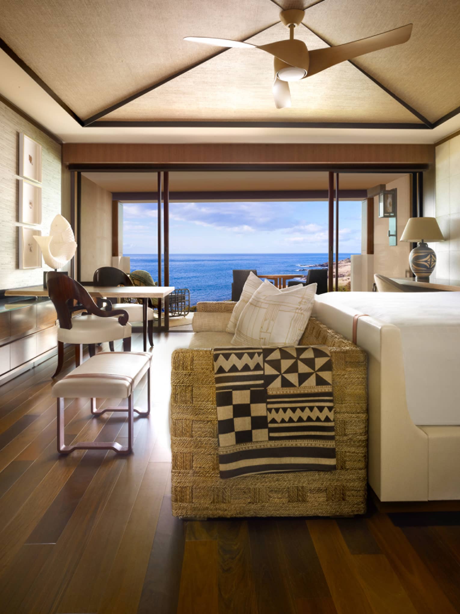 Oceanfront Room bed, small sofa and bench at foot, TV screen displaying ocean waves, rainbow