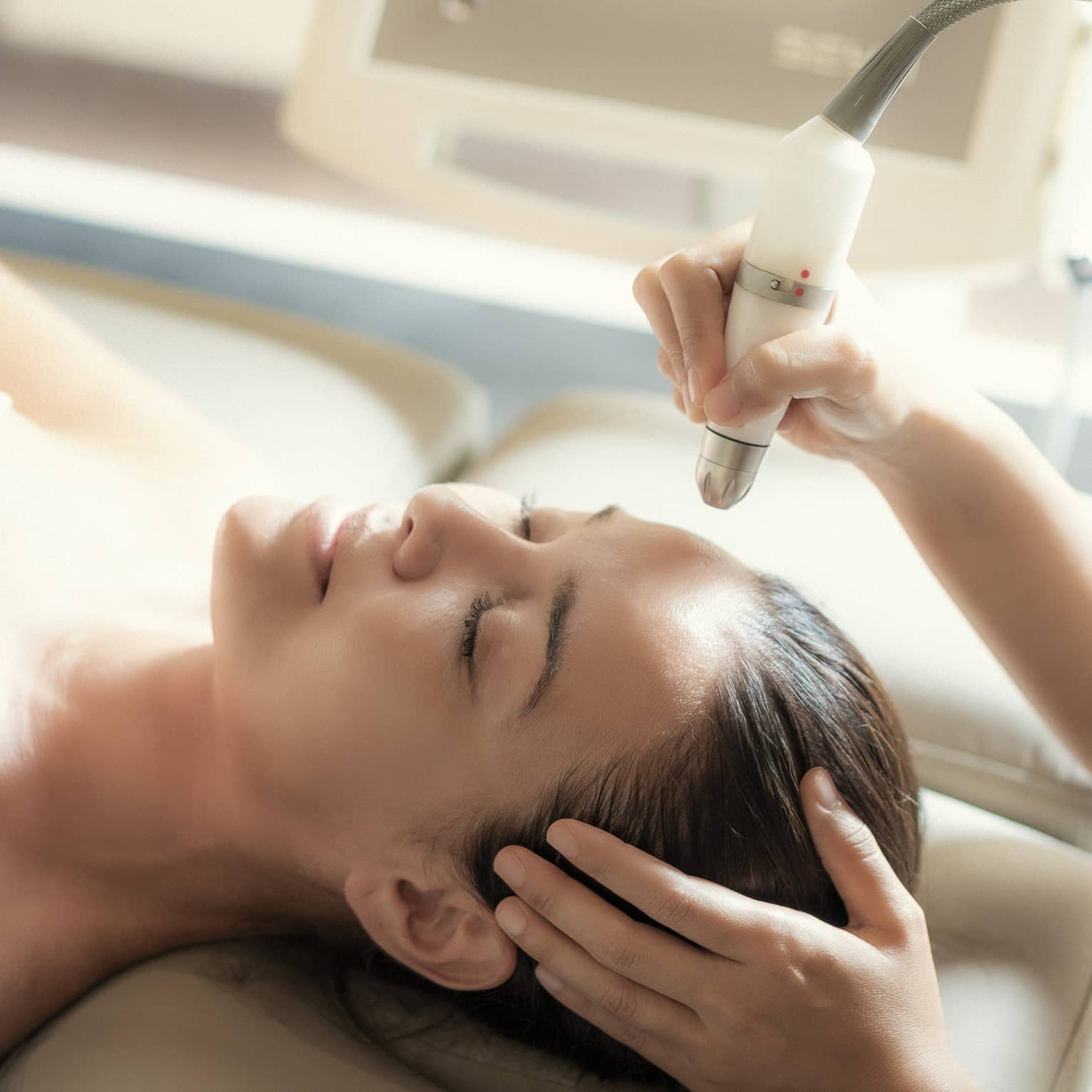 An aesthetician uses a tool on the face of a relaxing woman.