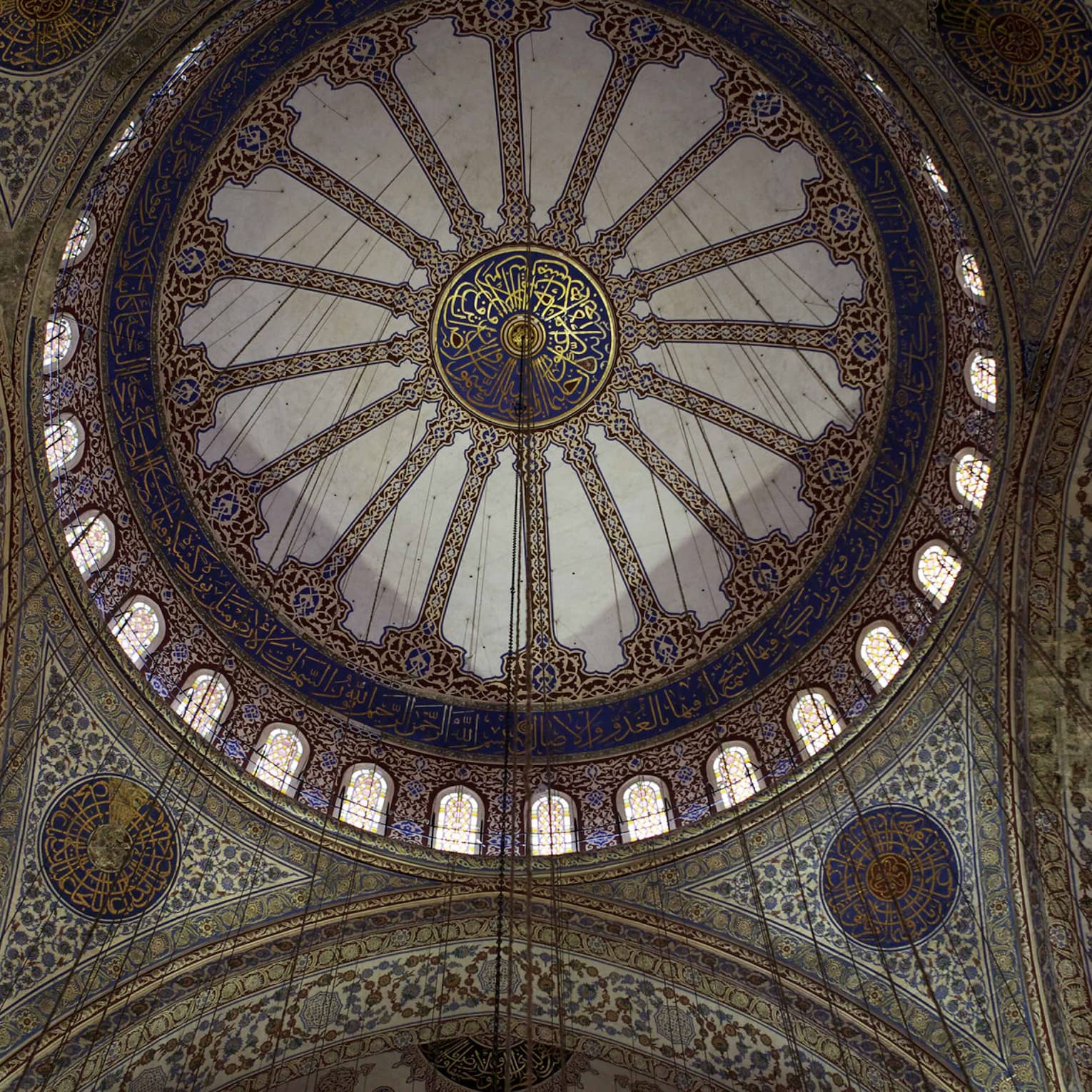Ceiling of the interior dome of a mosque, painted predominantly in blue with floral motifs and calligraphic inscriptions. 