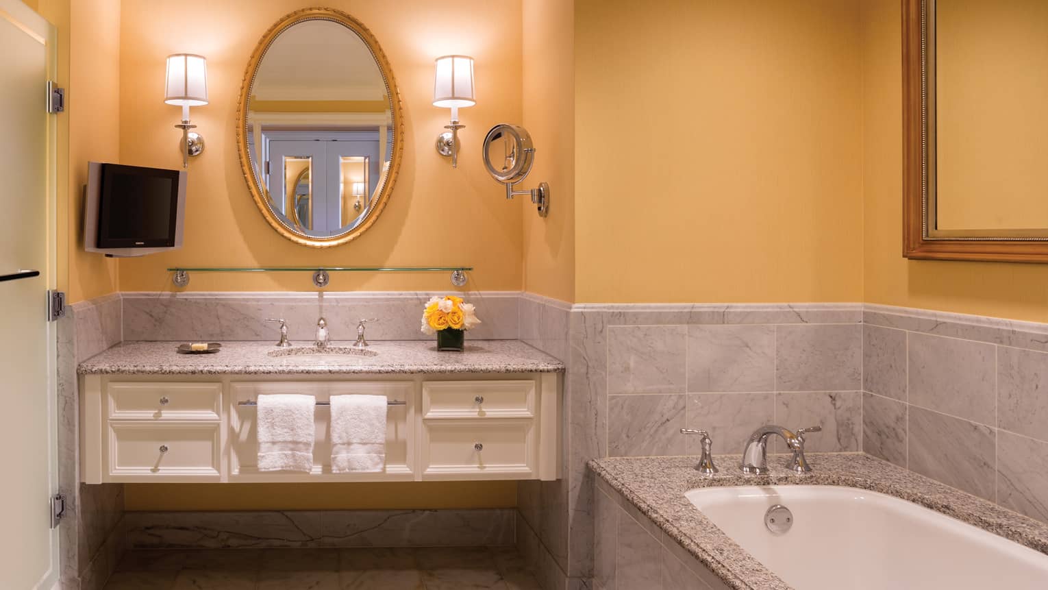 Deluxe Waterfall-View room bathroom yellow walls, flowers on vanity, sink, marble tub