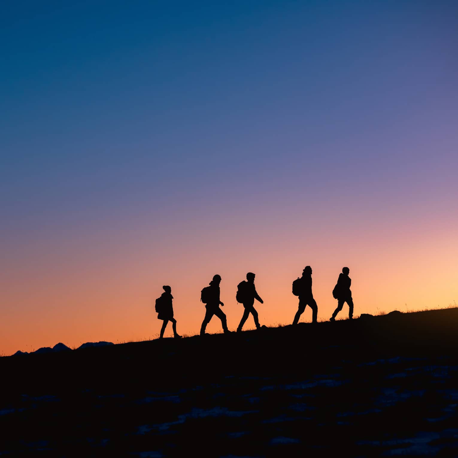 Group hikes on ridge at sunset