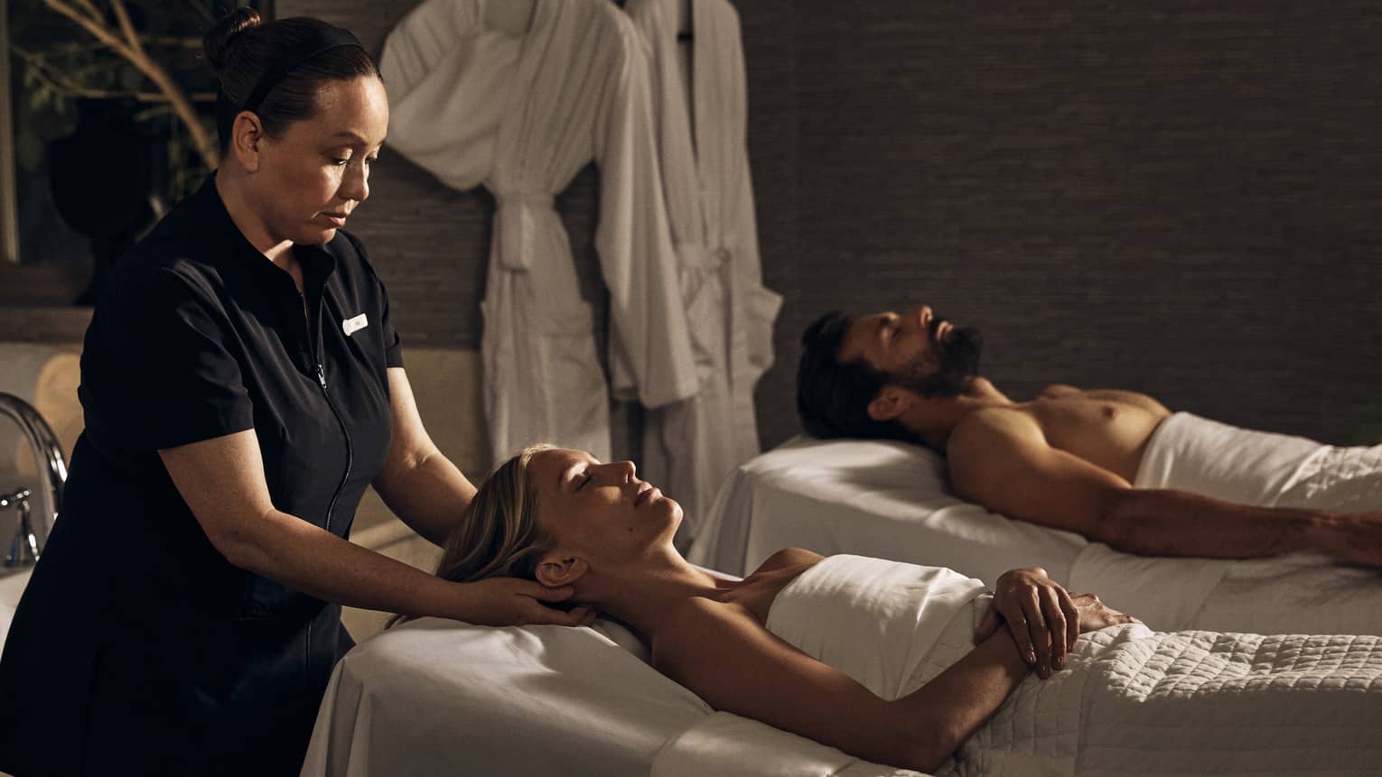 Two guests laying on massage tables in a room with a spa tub.