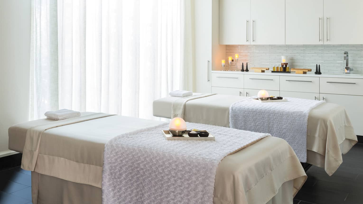 Couples Suite two massage tables with trays with glowing candles, salts in spa treatment room