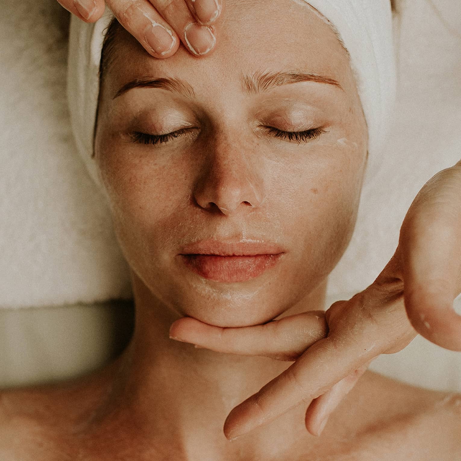 A woman reclines as a spa attendant performs a facial
