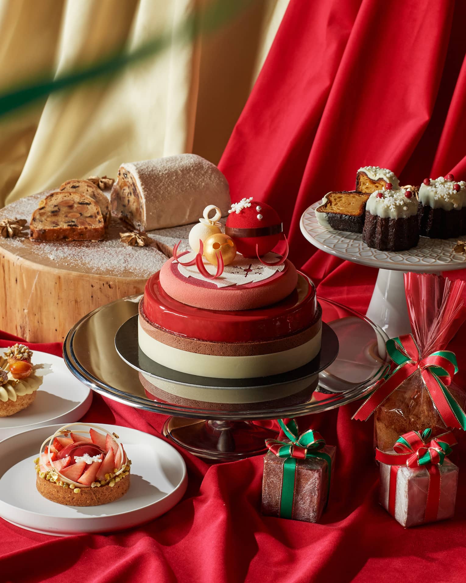 An assort of desserts on trays and red and gold sheets.