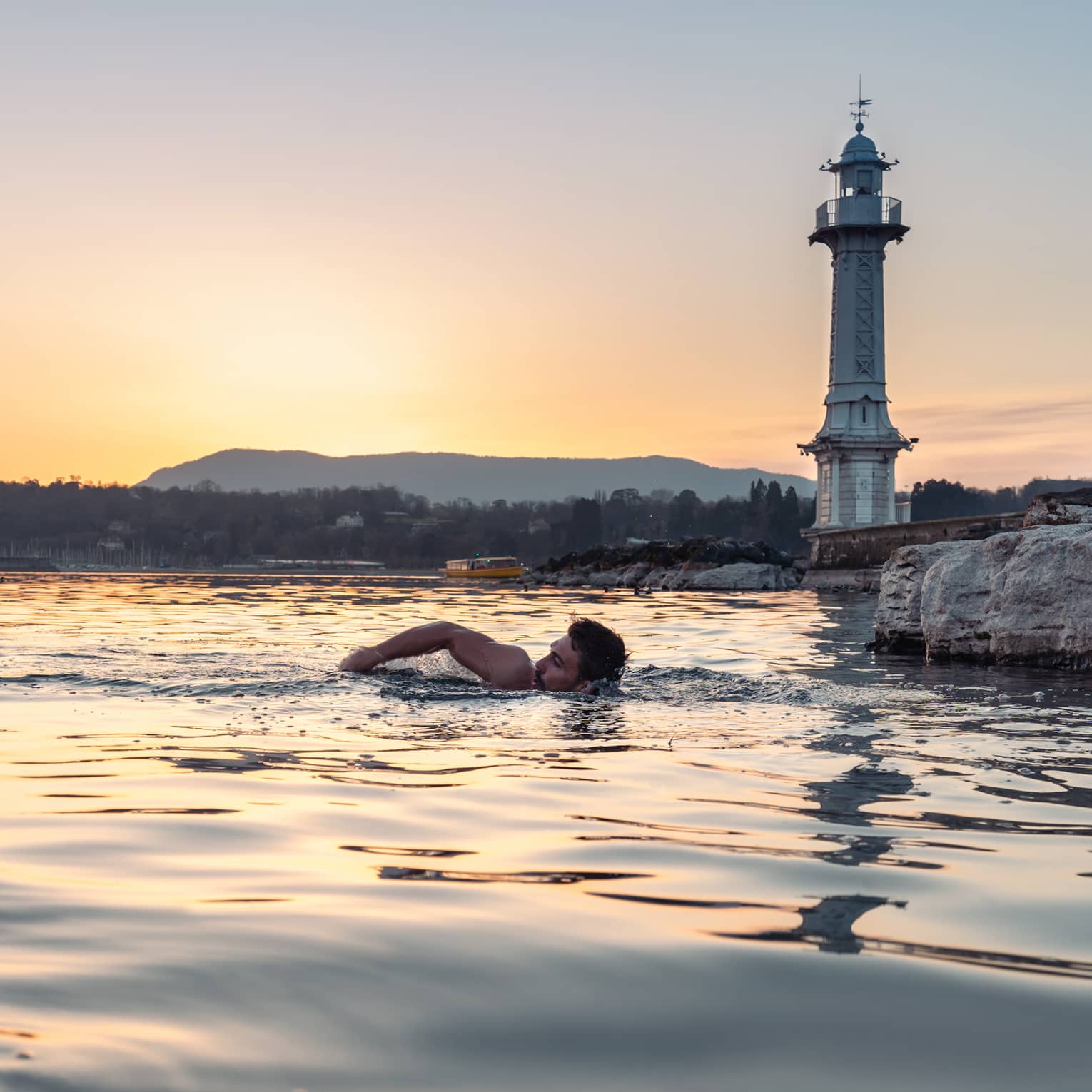 Person swimming in Lake Geneva at sunset