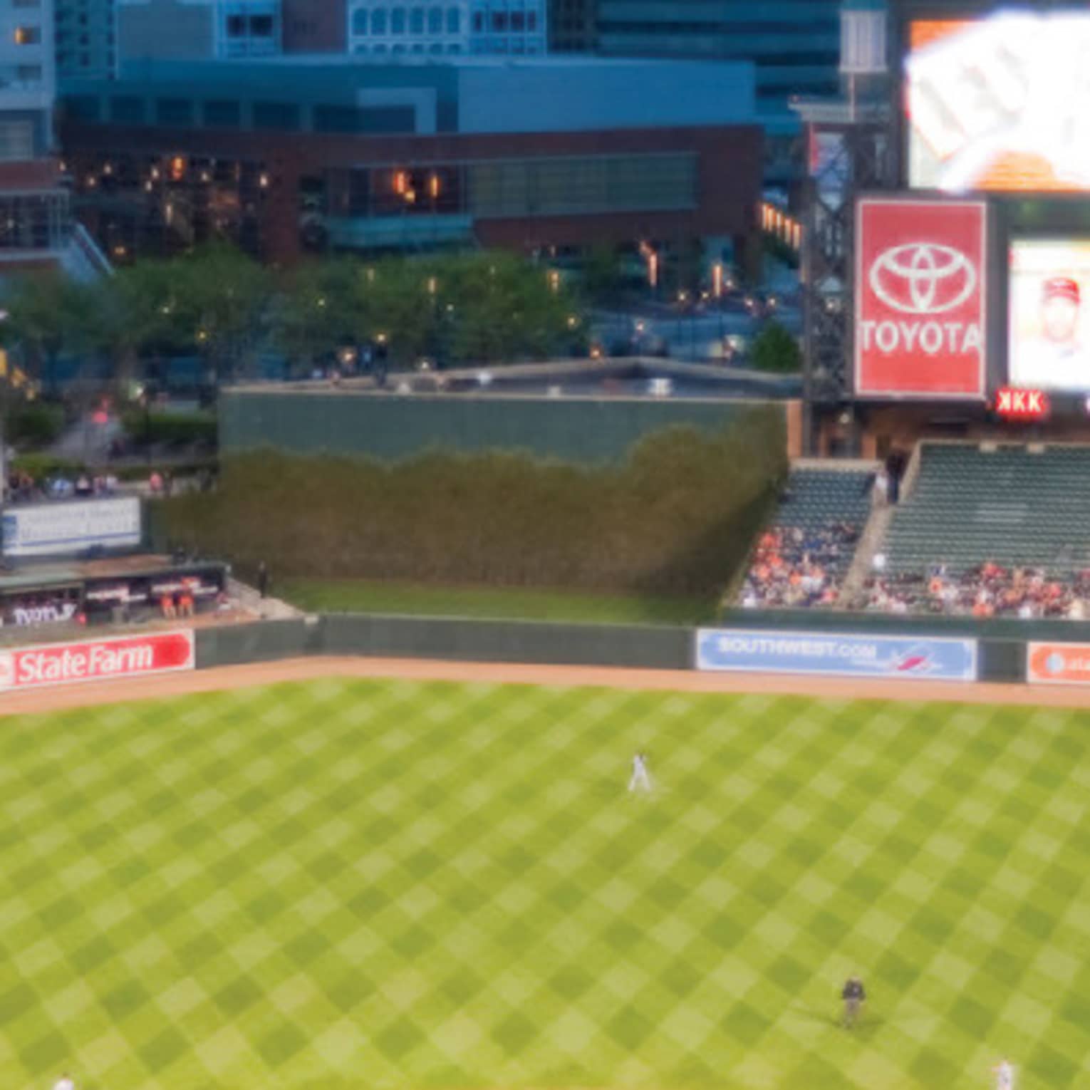 View over large open air baseball stadium with crowds in stands, city buildings in background
