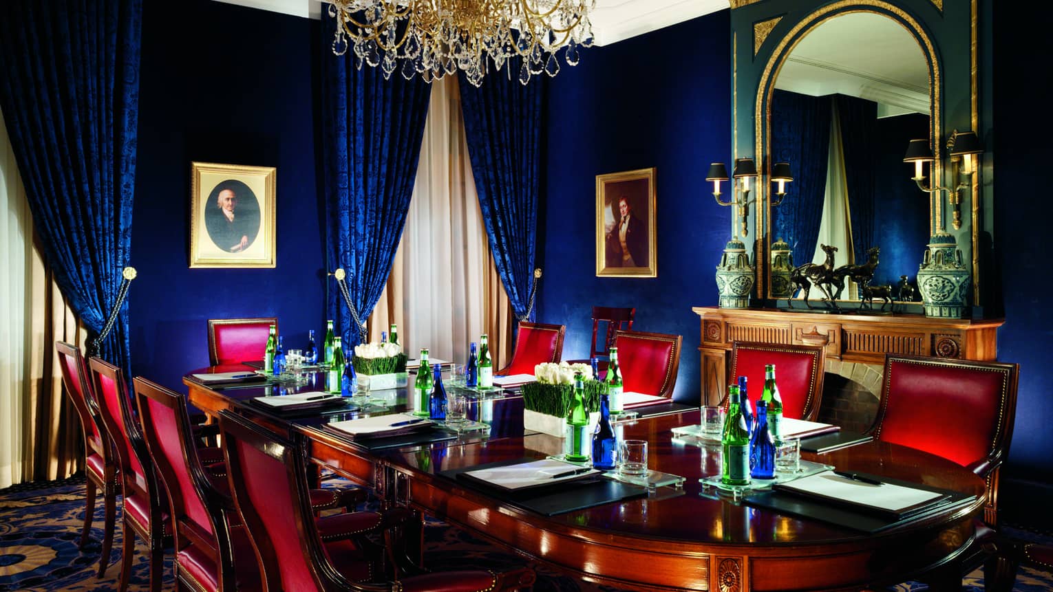 Red leather chairs around wood boardroom table in blue meeting room