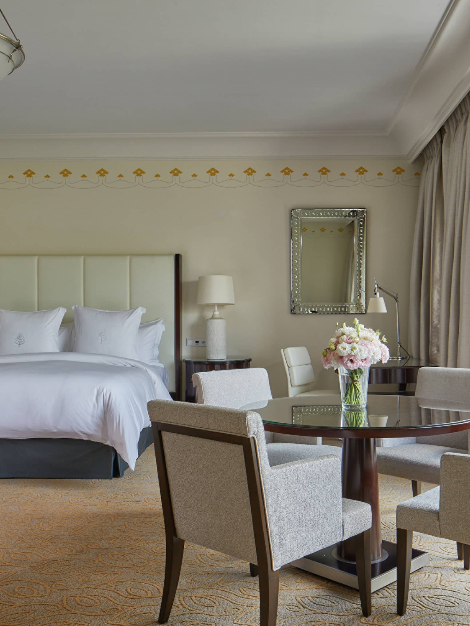 Spacious hotel room with king bed, round dining table, four chairs and large window with garden view