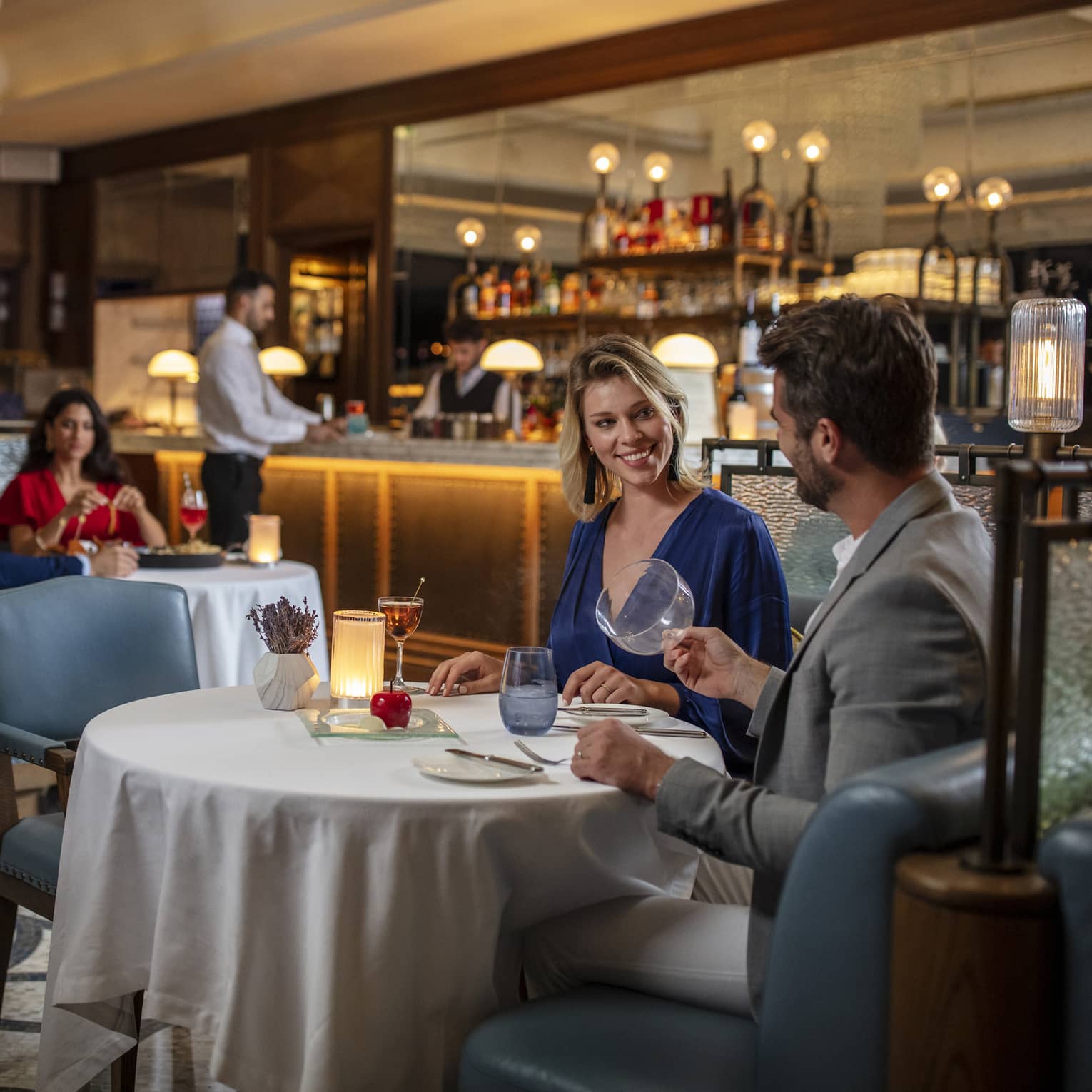 A couple sits at a table for two in a dimly lit restaurant