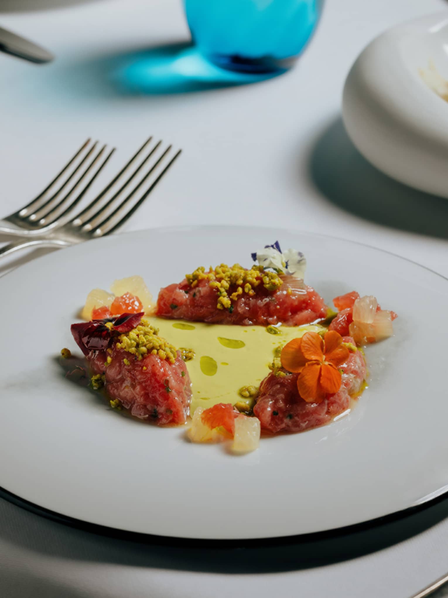 Tuna tartare plated on a white plate with a silver rim