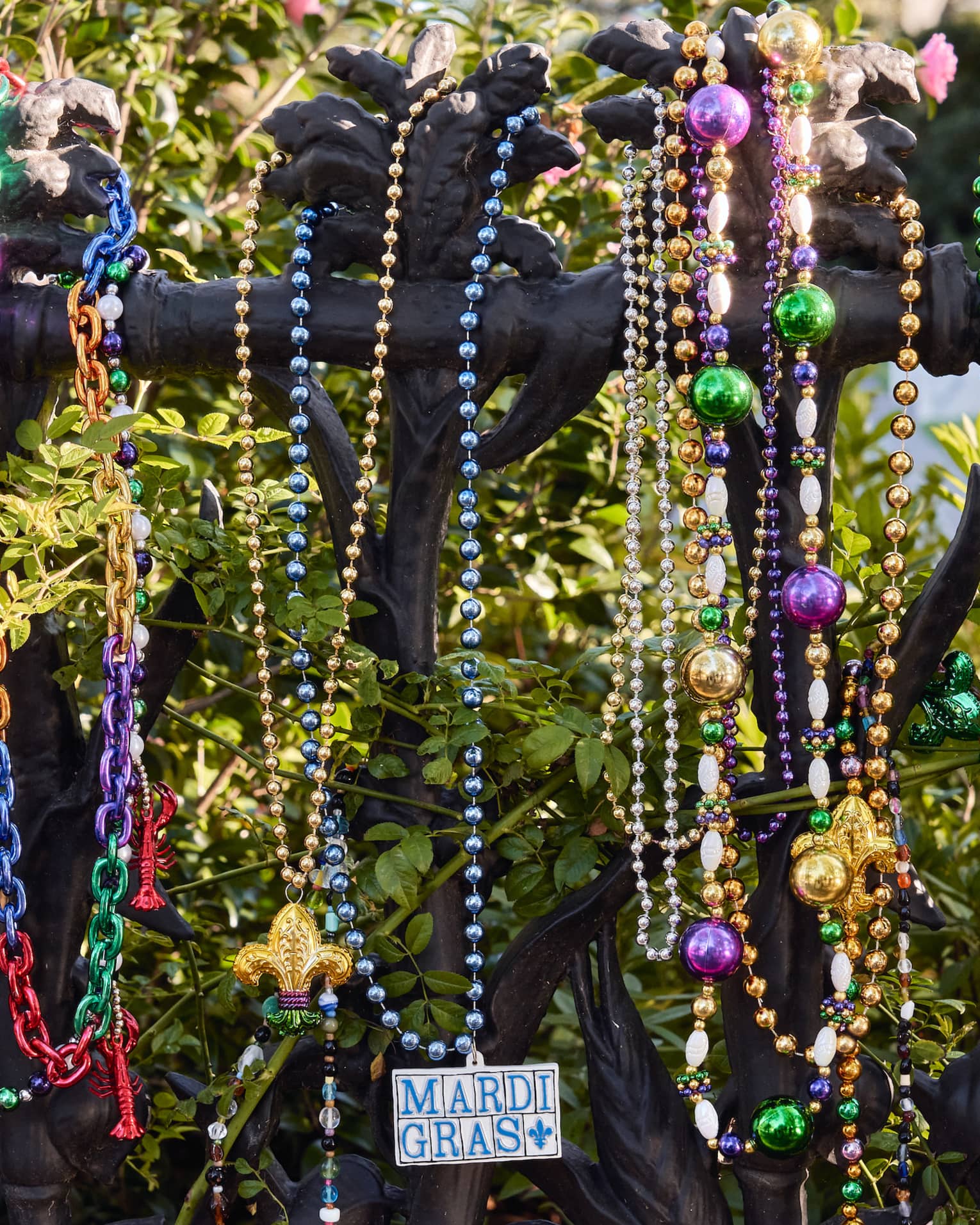 Strands of colourful Mardi Gras beads hanging on a wrought iron post