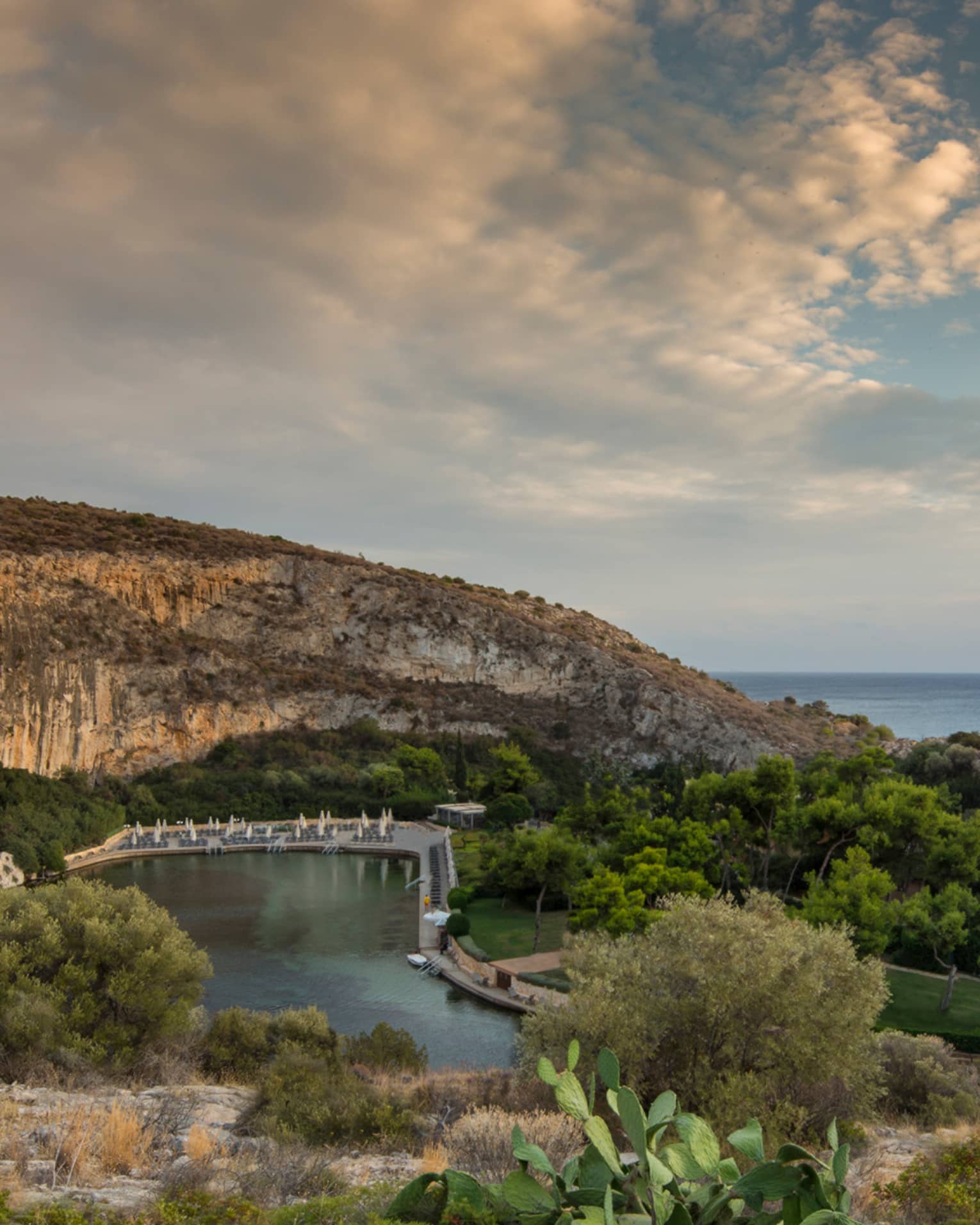 View of Vouliagmeni with rocky hill, green trees and shrubs overlooking ocean