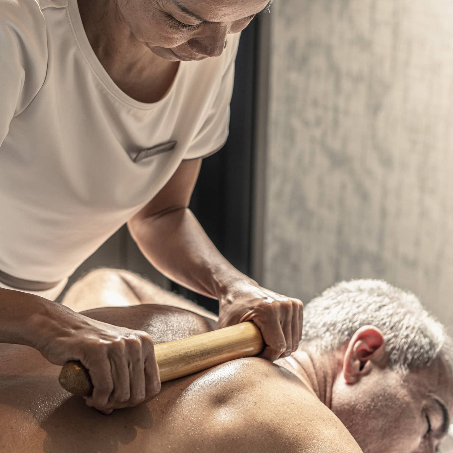Massage therapist performs a bamboo massage on male guest