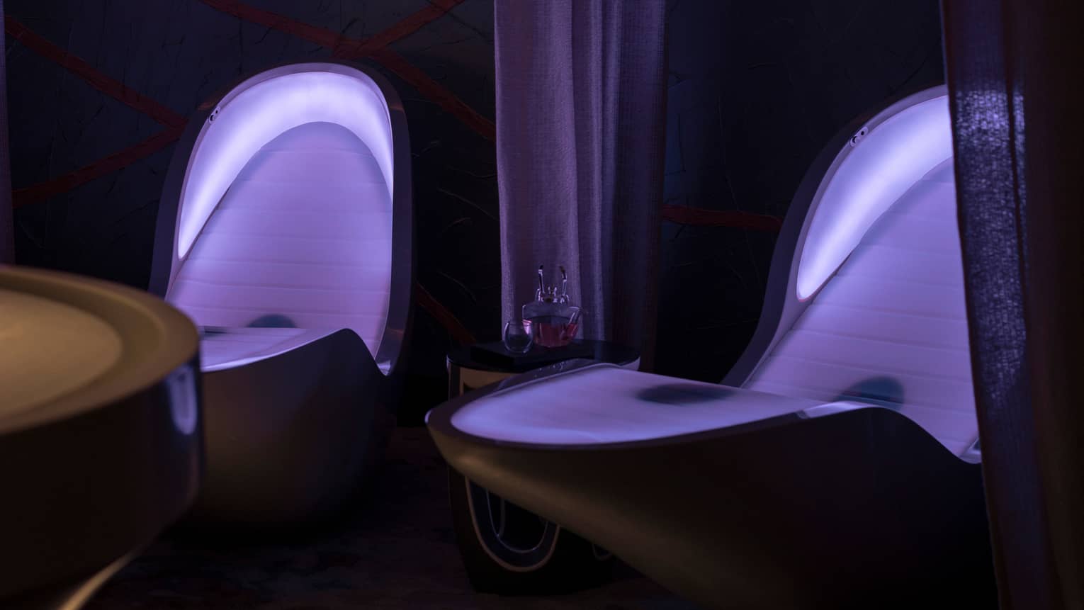 Illuminated four senses loungers in dark room