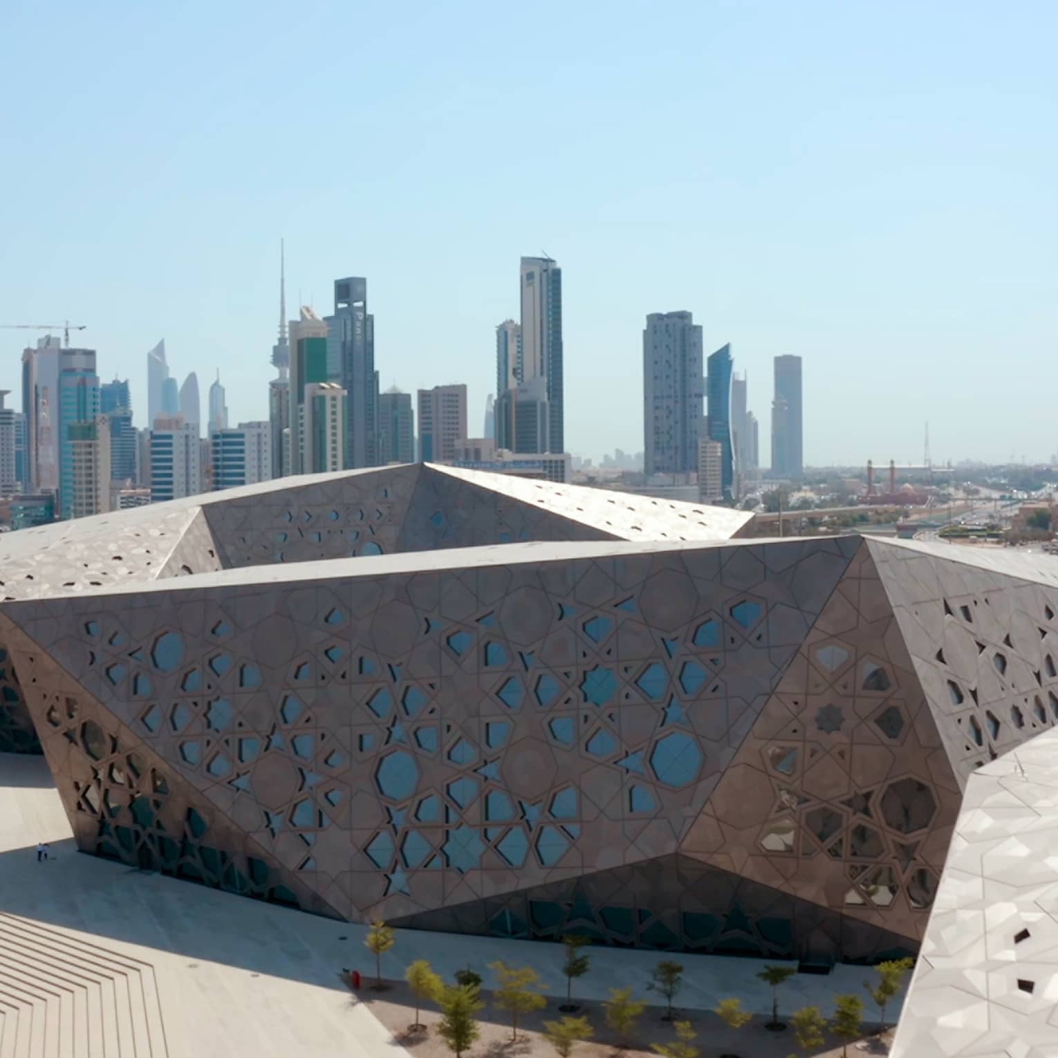 Metal-and-glass angluglar building with the Kuwait skyline in the background