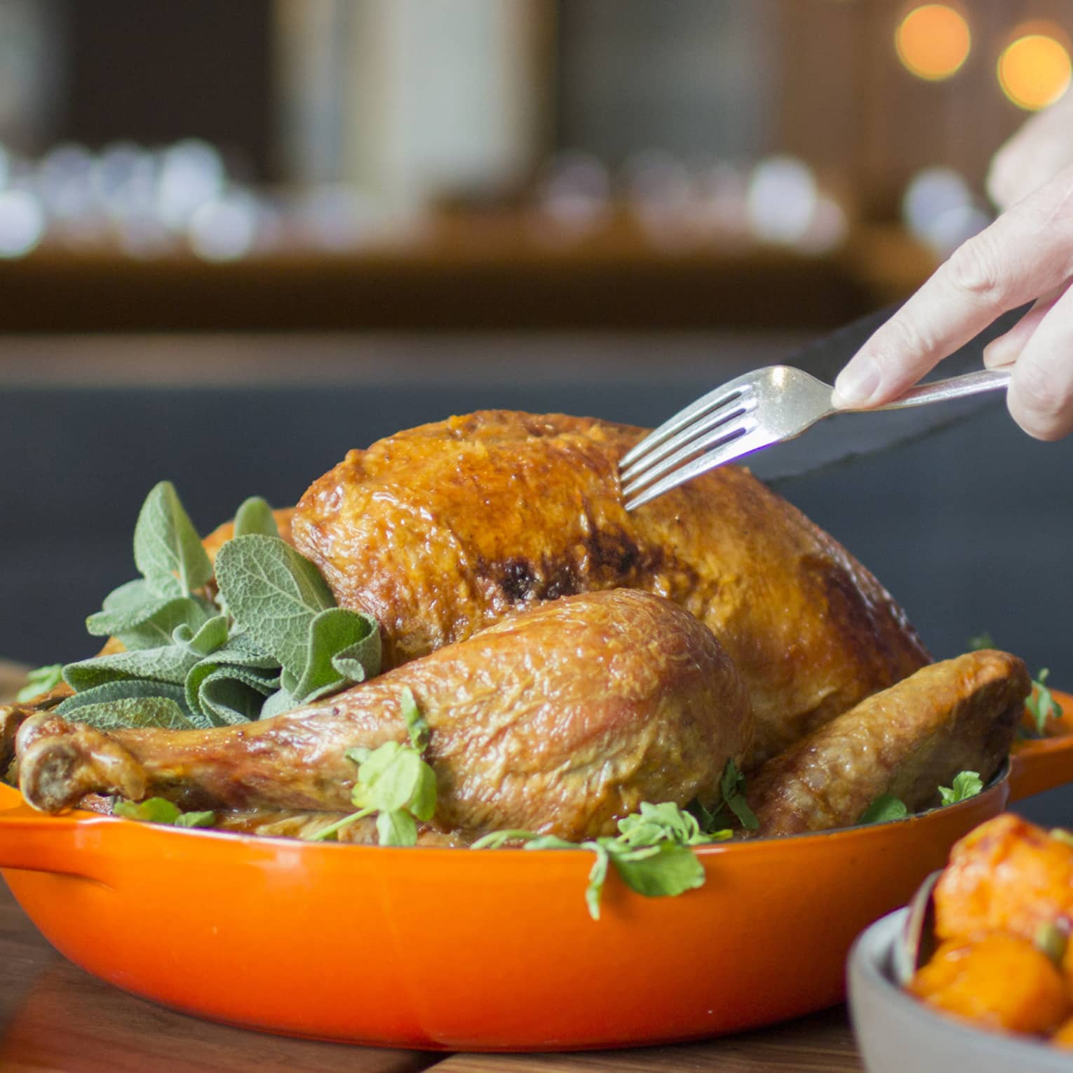 Thanksgiving turkey in orange dish being served by server holding fork