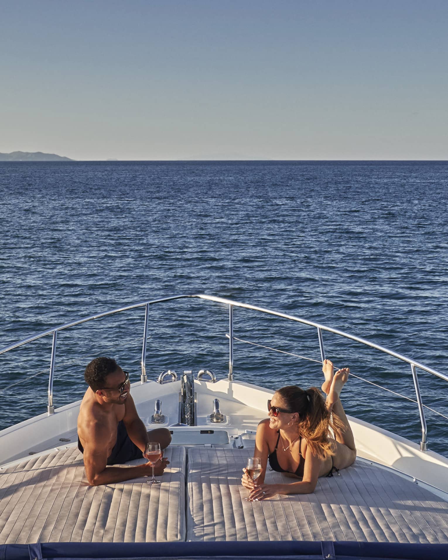 Man and woman lay on front of yacht