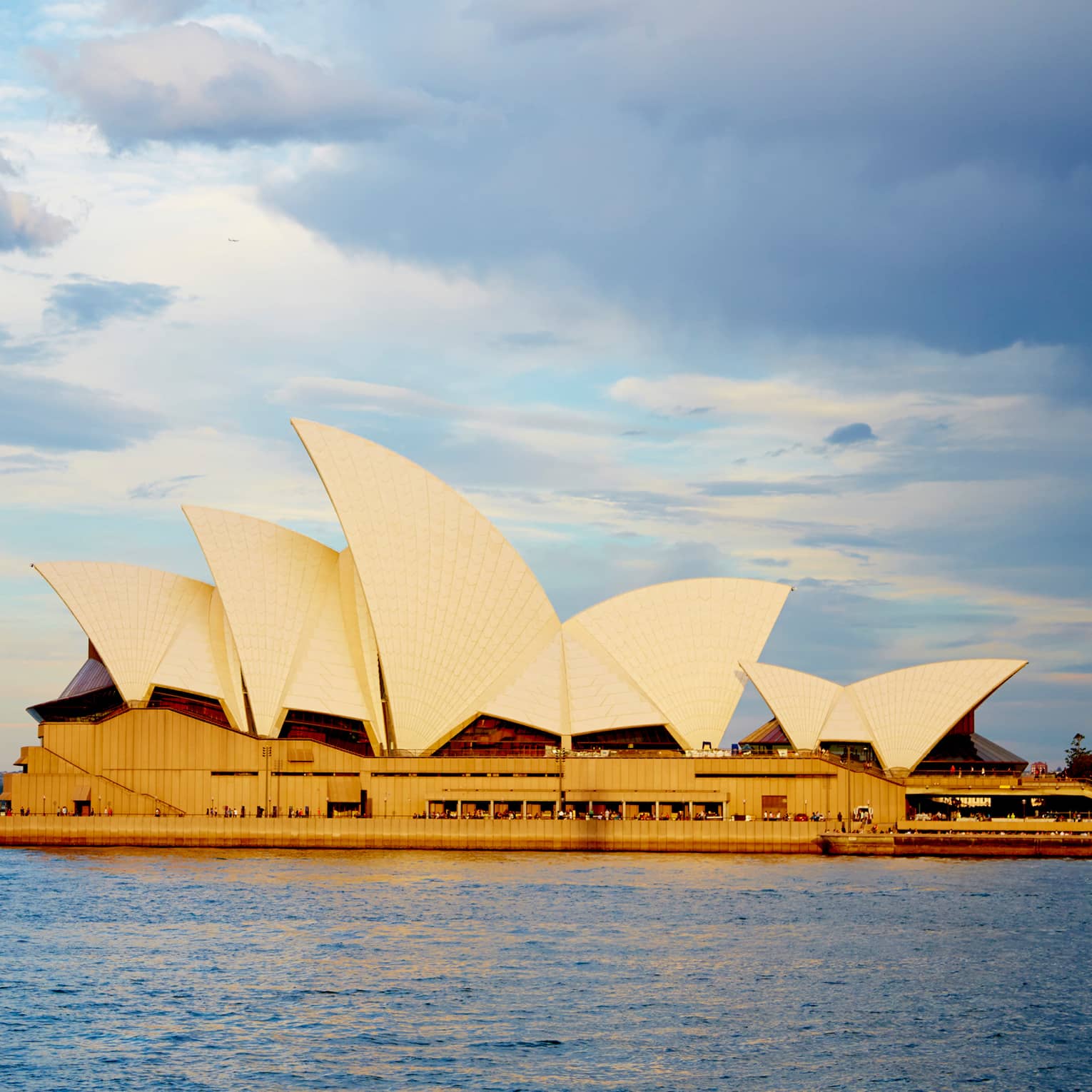 View of Sydney Opera House with its white, sailboat-like roof from harbour