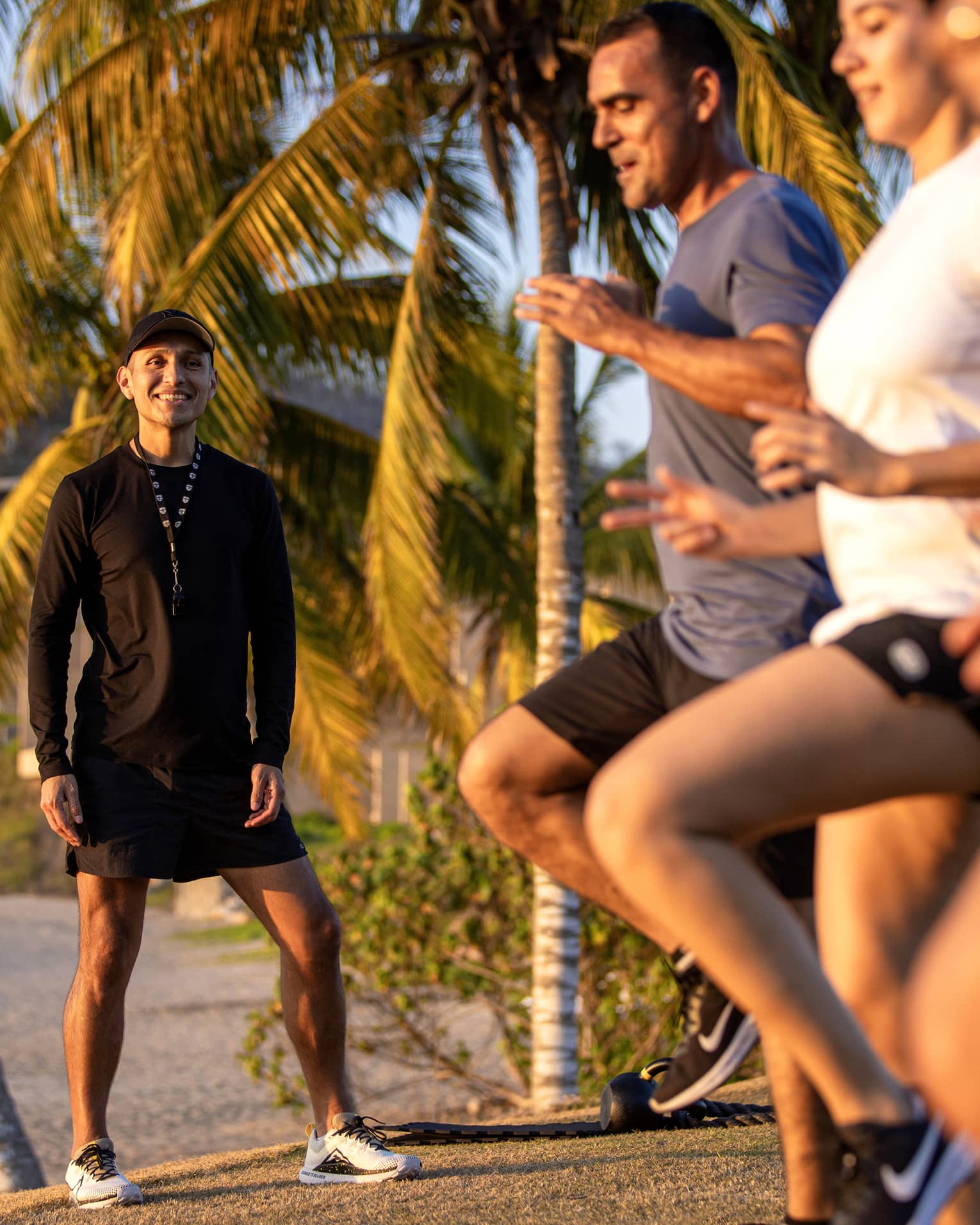 Fitness instructor leading an outdoor workout class with three guests.