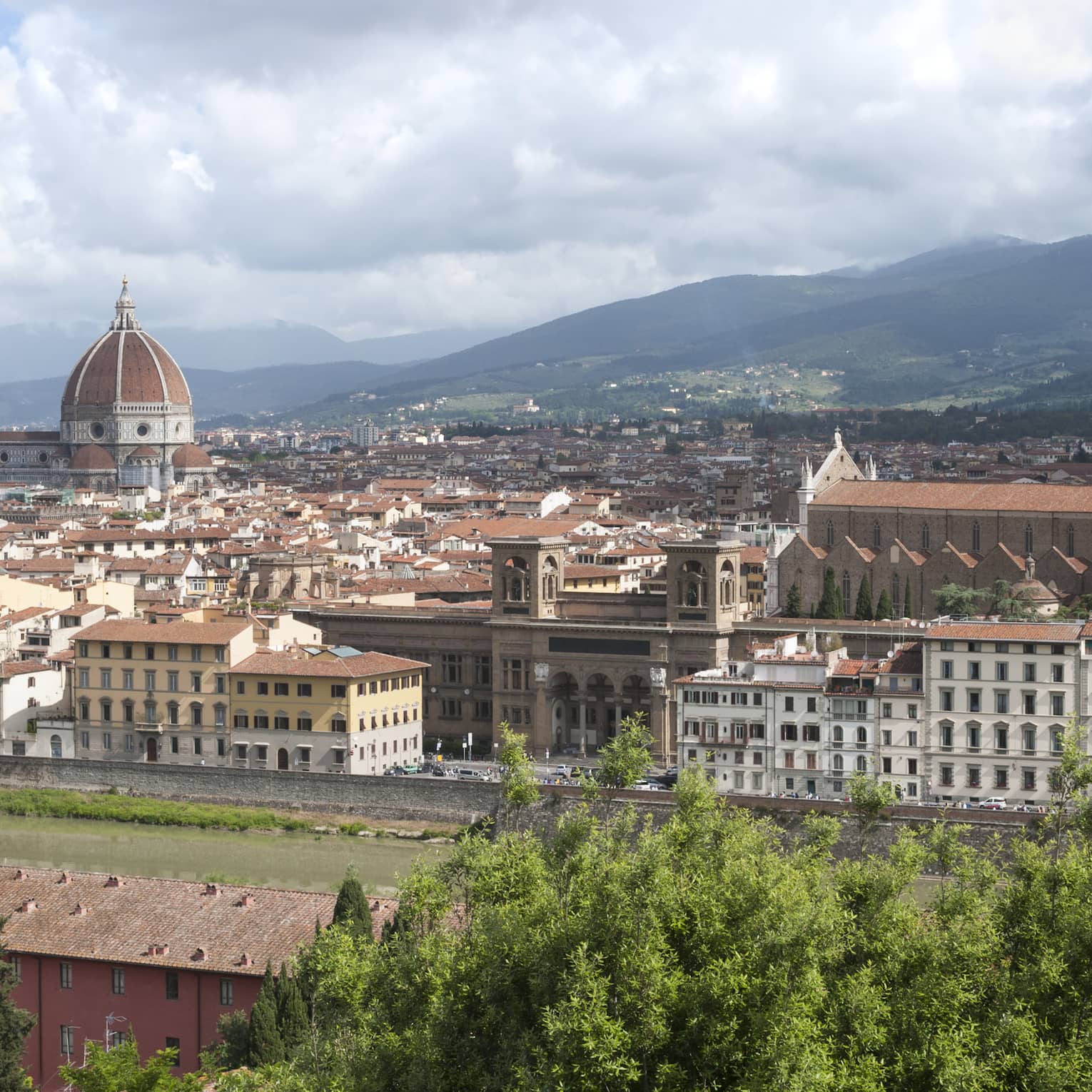 A hilltop view of the Dome of Santa Maria del Fiore, Basilica of Santa Croce and the terracotta tiled rooftops of Florence.