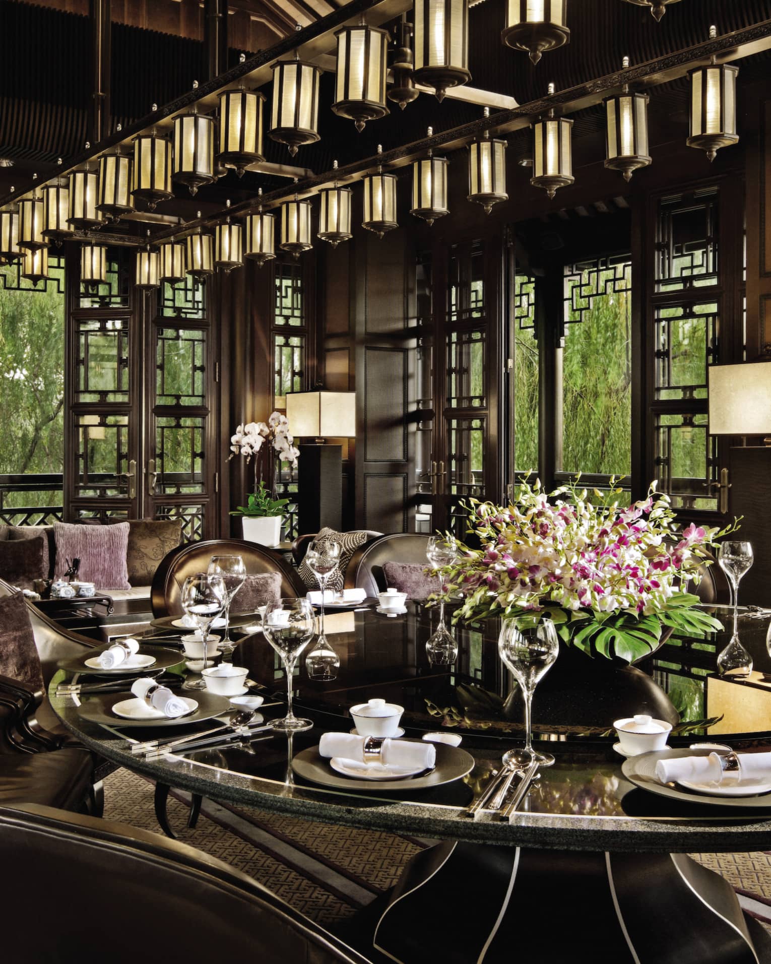 Large round, black, shiny dining table under lantern chandelier at Jin Sha