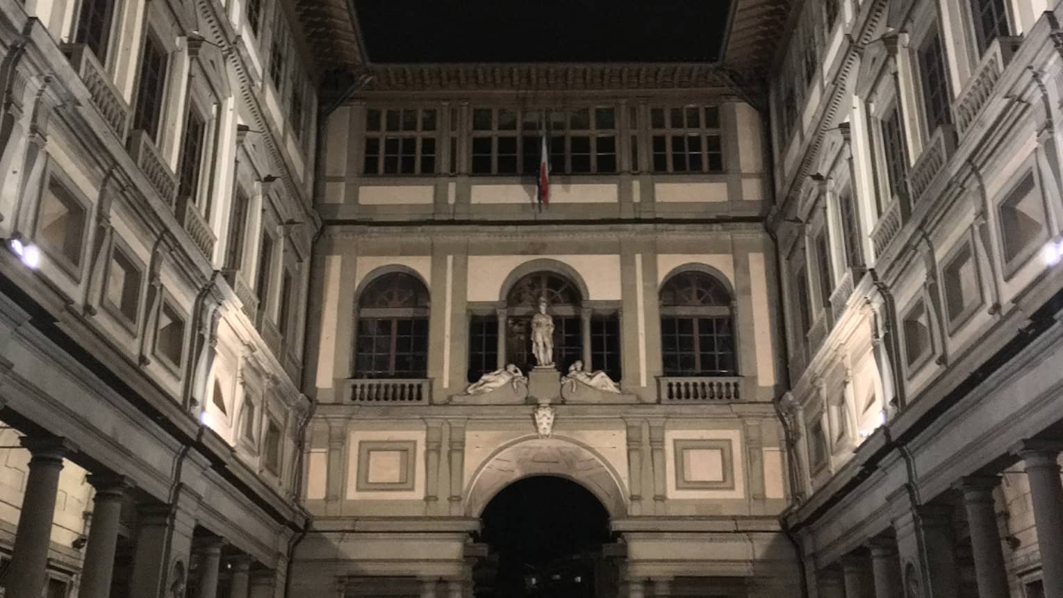 Looking up at Uffizi Gallery architecture, stone statues at night