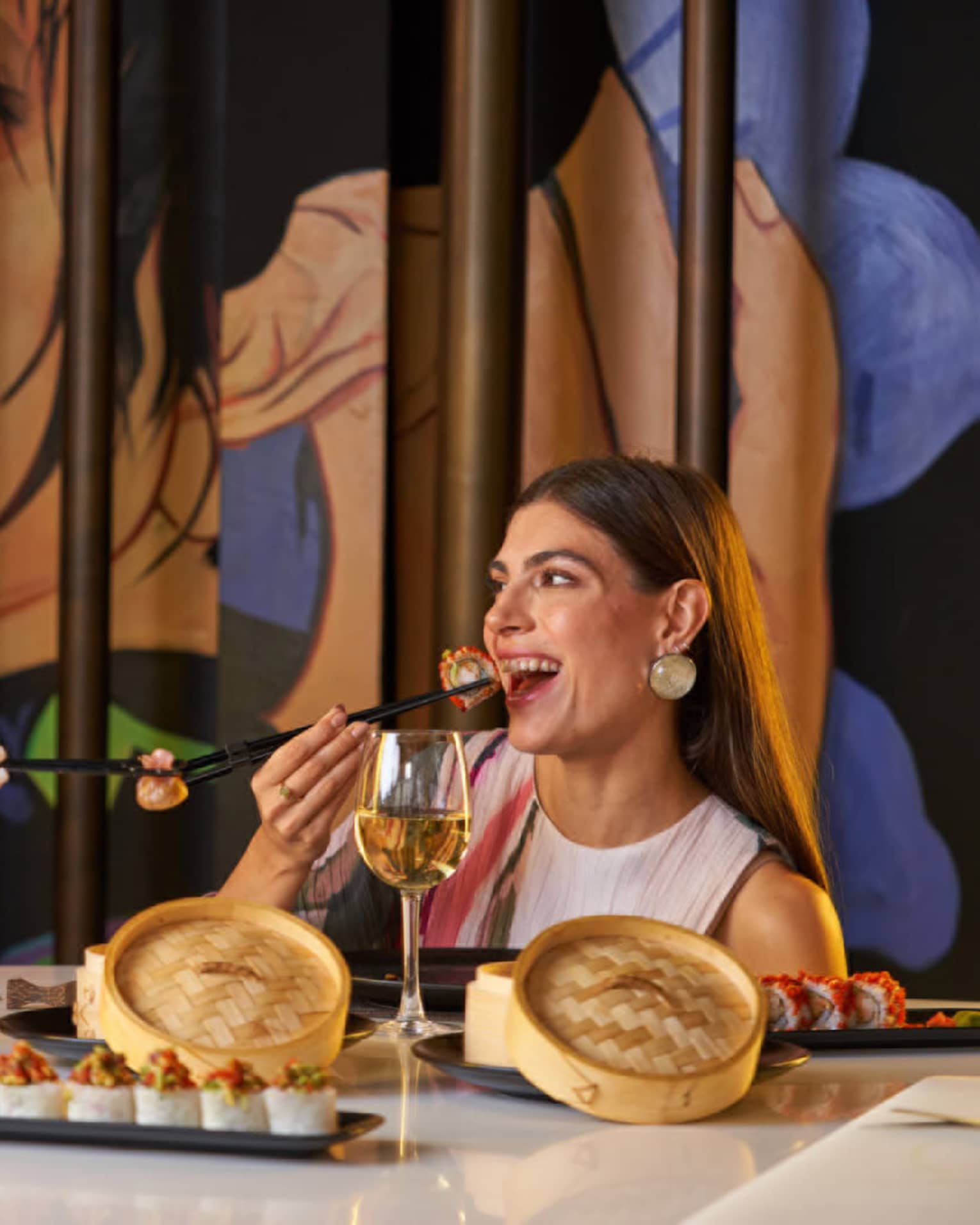 Two people enjoy dim sum with chopsticks from small bamboo steamer baskets are restaurant