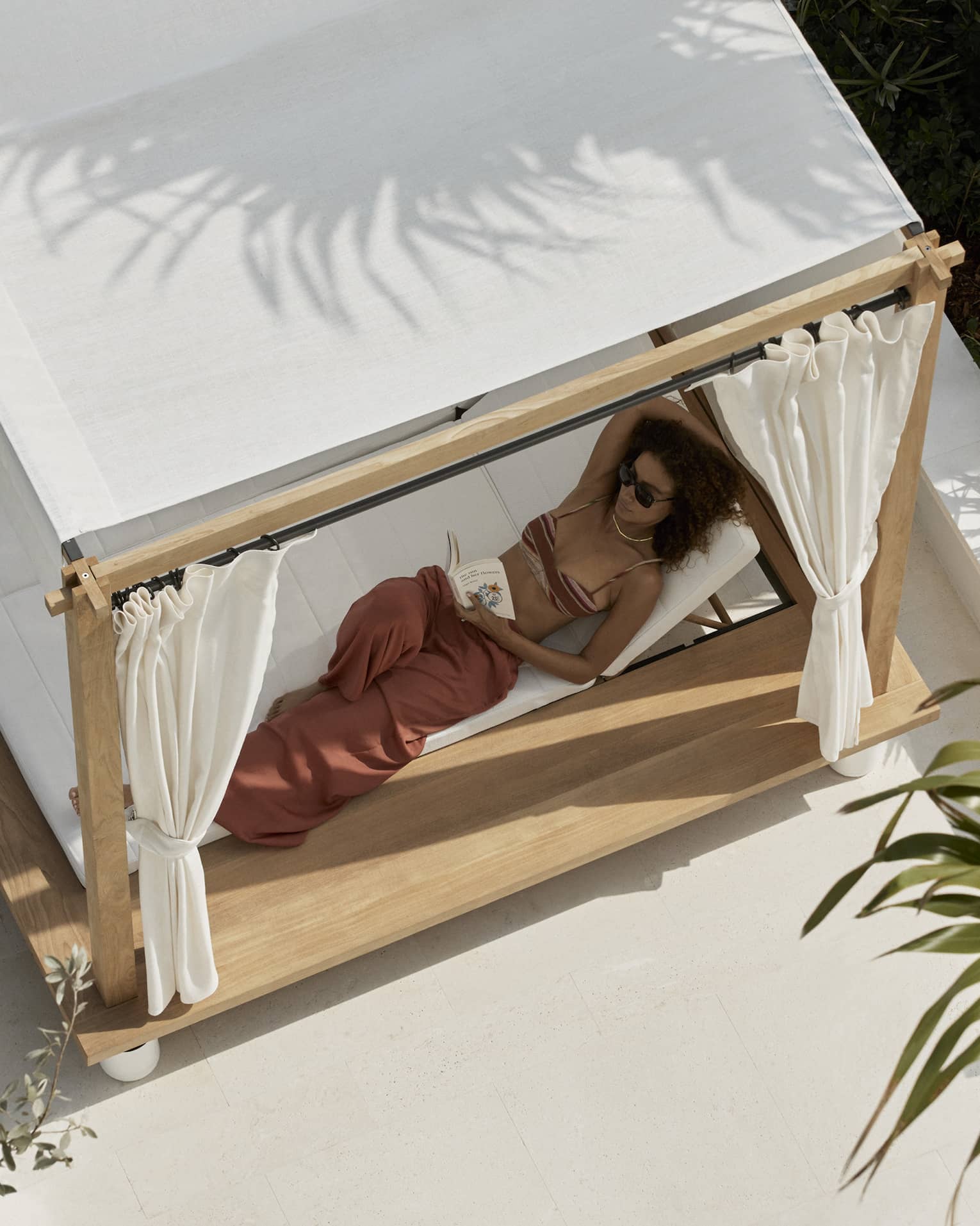 Aerial view of woman lounging in a covered poolside daybed
