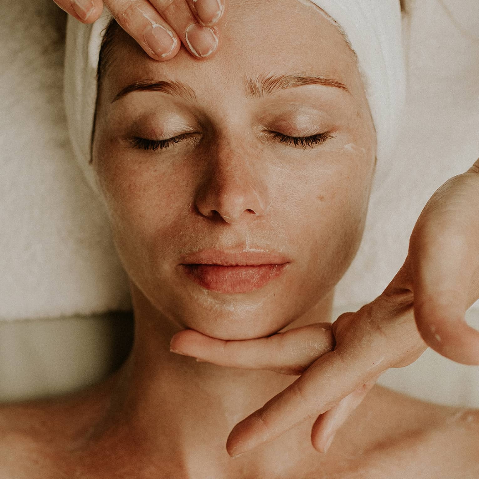 A woman reclines as a spa attendant performs a facial
