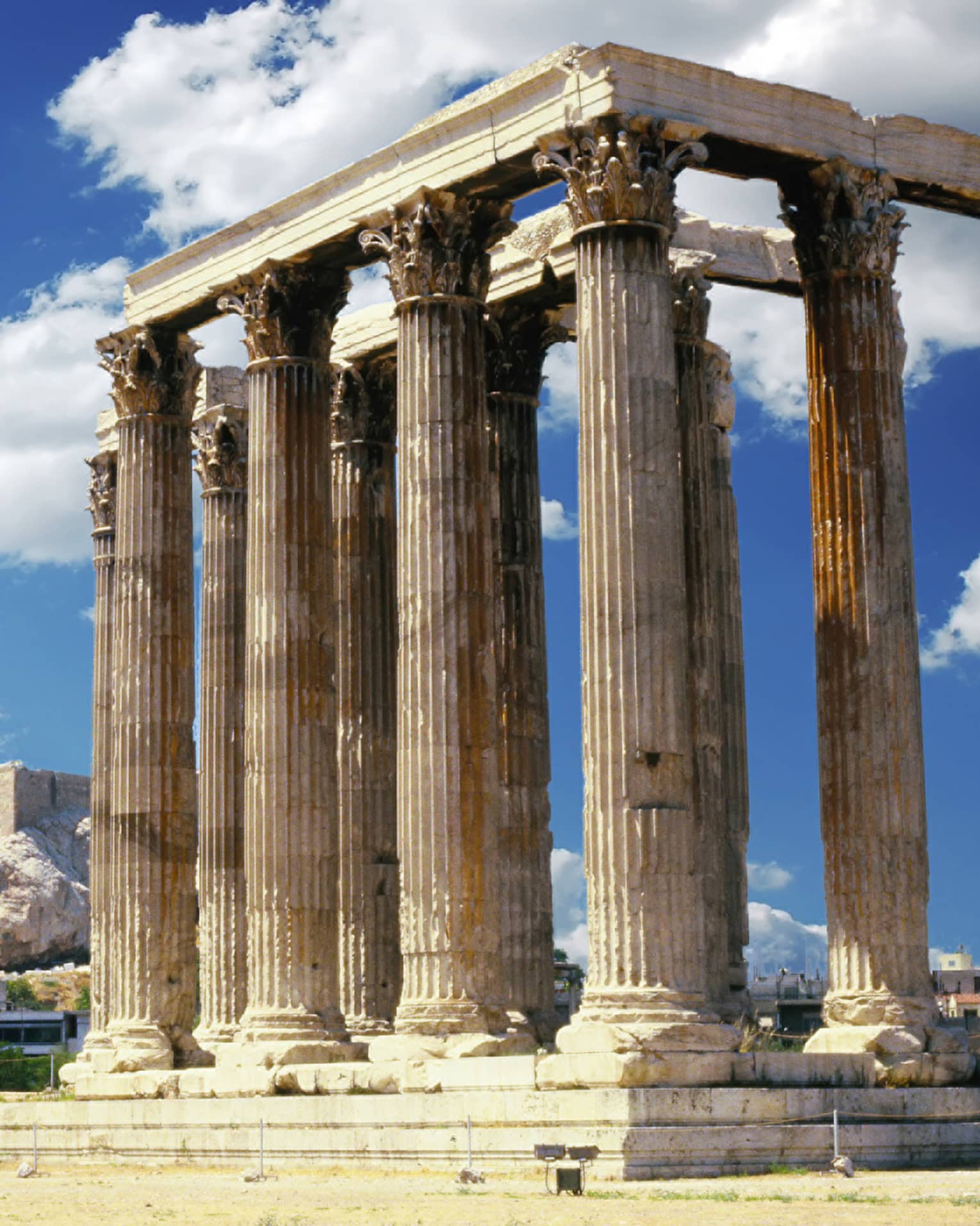 A temple with towering columns featuring intricate designs; more ruins and the Parthenon prominent in the background.