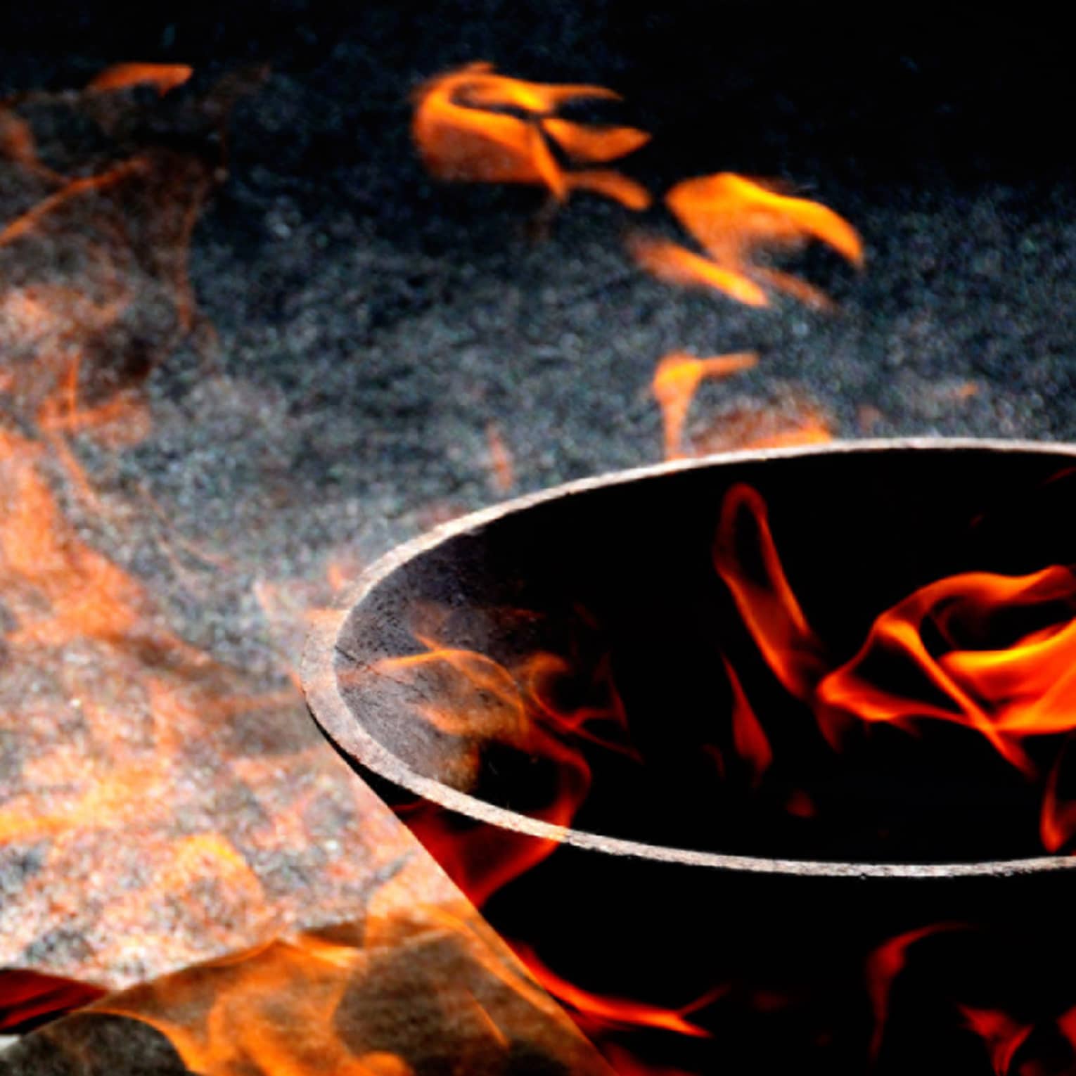 Close-up view of orange-red flames appearing to float in and around a stone bowl set against a variegated dark background.