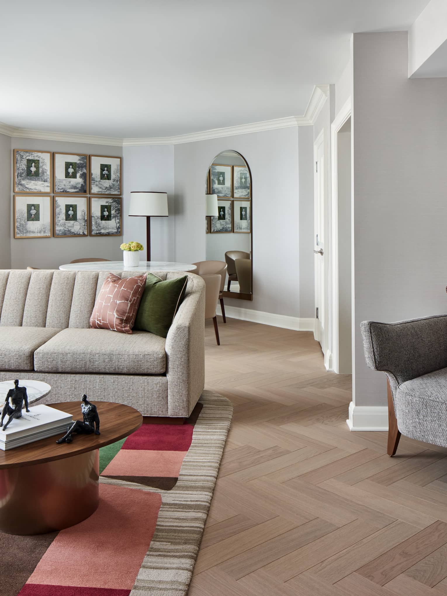 Stylish living room of a hotel suite, with sofa, table, dining table, parquet flooring and colorful red and beige area rug